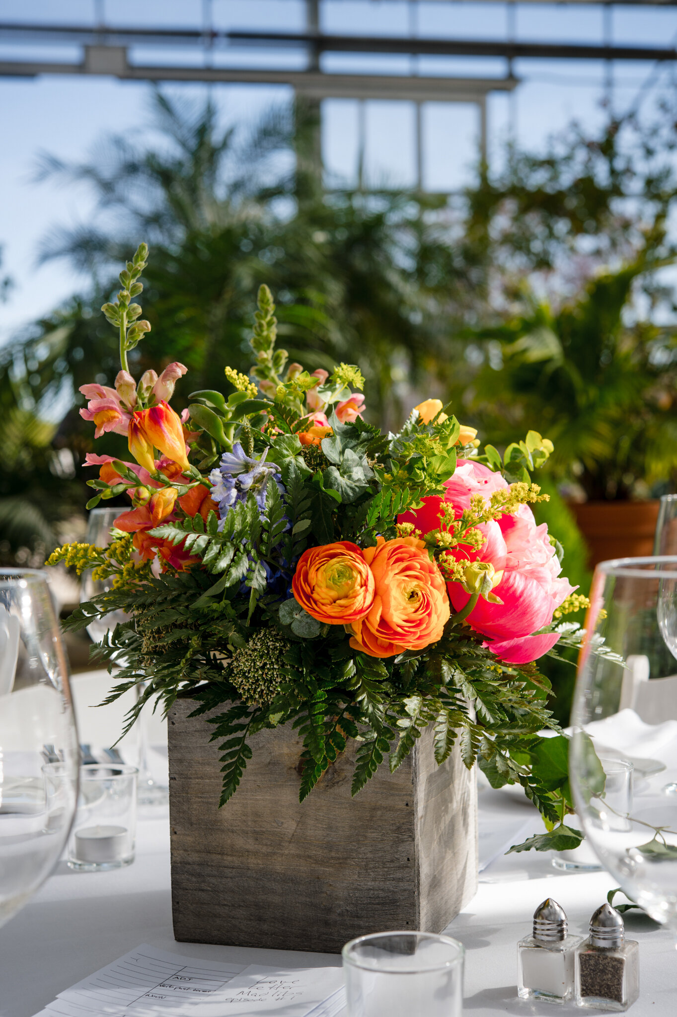 Close up of bright floral centerpiece on guest reception table during queer wedding at Roger Williams Botanical Center Providence Rhode Island Michelle Schapiro Photography