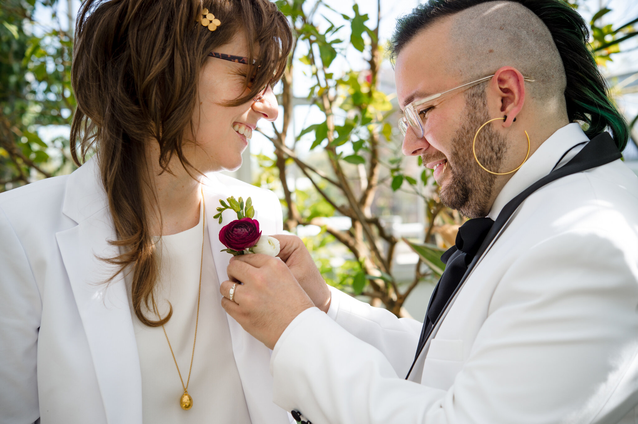 Marrier pins boutonierre on partner's suit while getting ready before ceremony at Roger Williams Botanical Center Providence Rhode Island Michelle Schapiro New England LGBTQ Couple Photographer