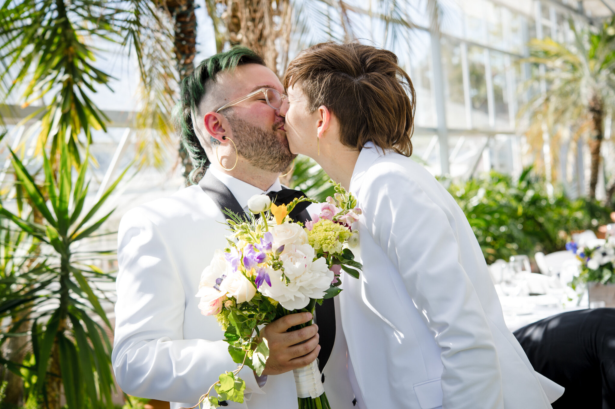 Marriers kiss while holding bouquet before ceremony at Roger Williams Botanical Center Providence Rhode Island Michelle Schapiro New England LGBTQ Couple Photographer