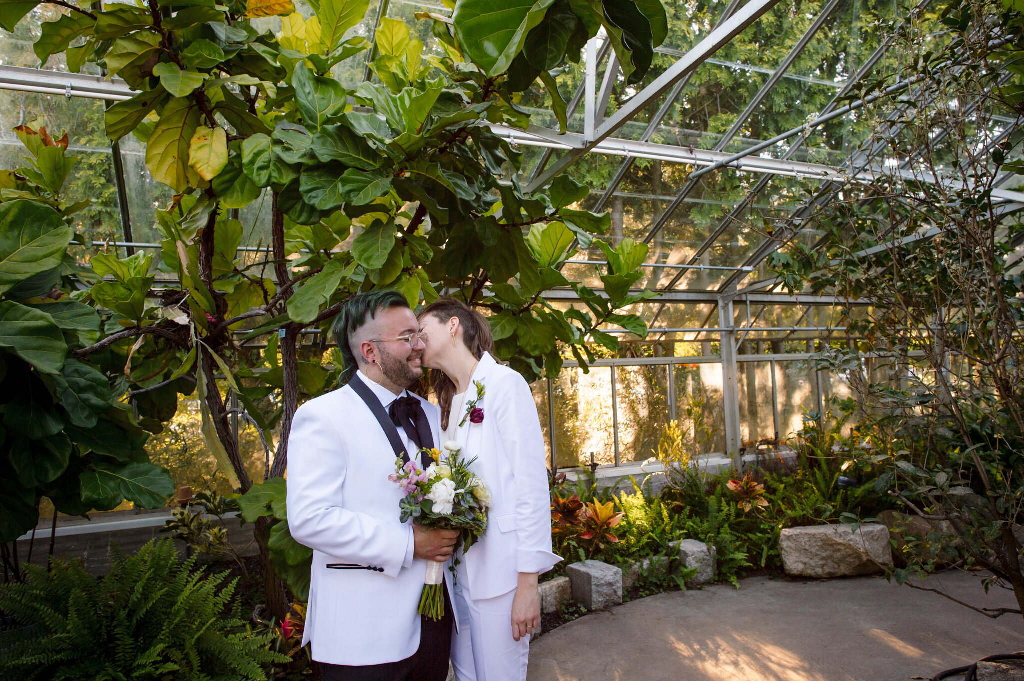 Marriers smile and kiss in greenhouse after ceremony at Roger Williams Botanical Center Providence Rhode Island Michelle Schapiro New England Portrait Photographer