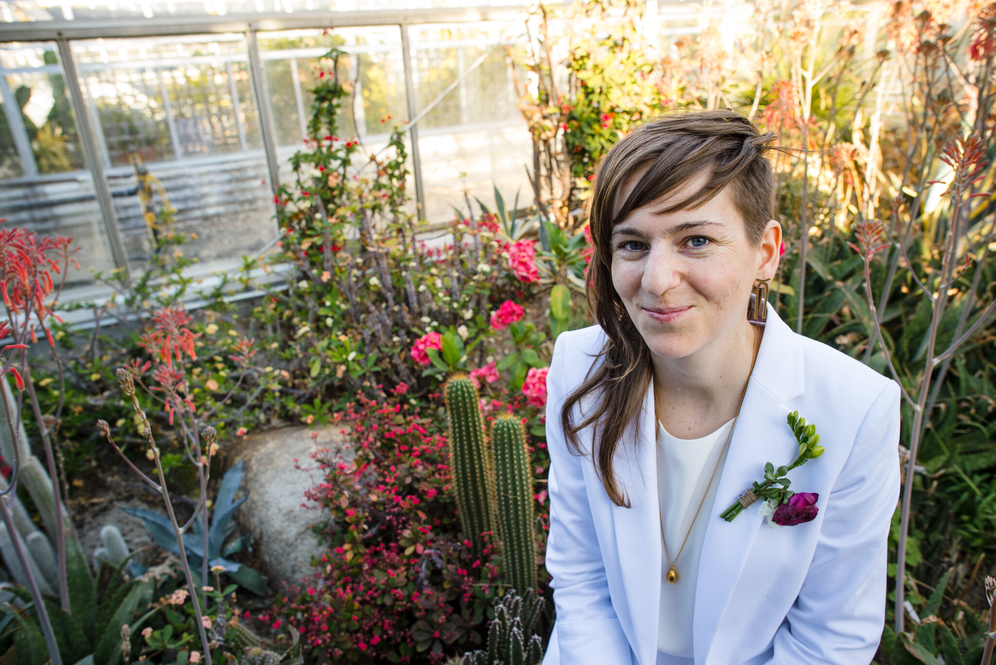 Portrait of smiling marrier in white suit surrounded by flowers and cacti at Roger Williams Botanical Center Providence Rhode Island Michelle Schapiro New England Portrait Photographer