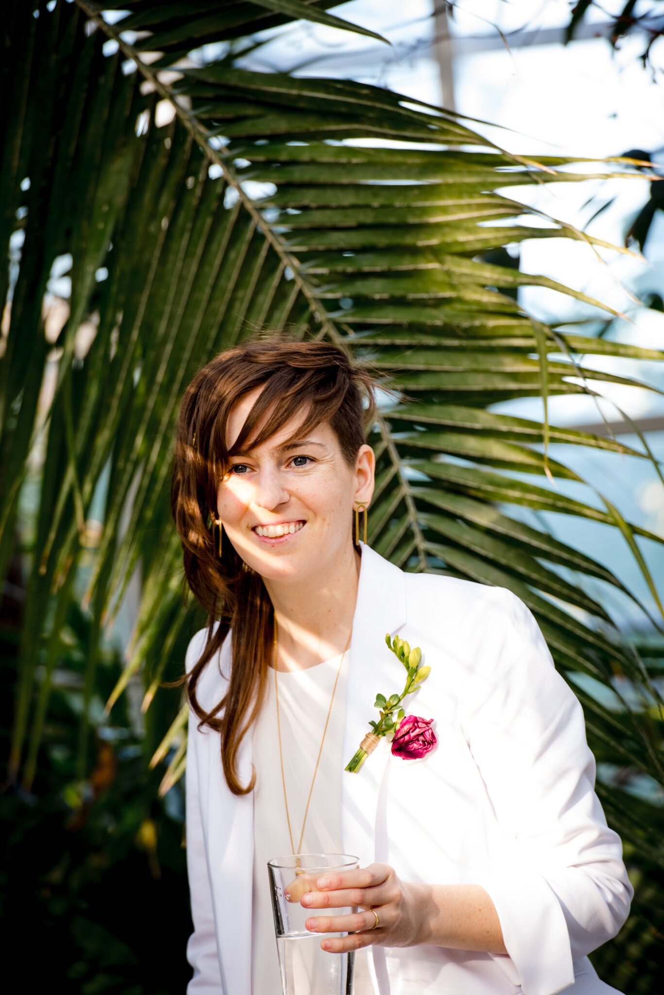 Marrier in white suit holds champagne glass during wedding reception at Roger Williams Botanical Center Providence Rhode Island Michelle Schapiro New England LGBTQ Photographer