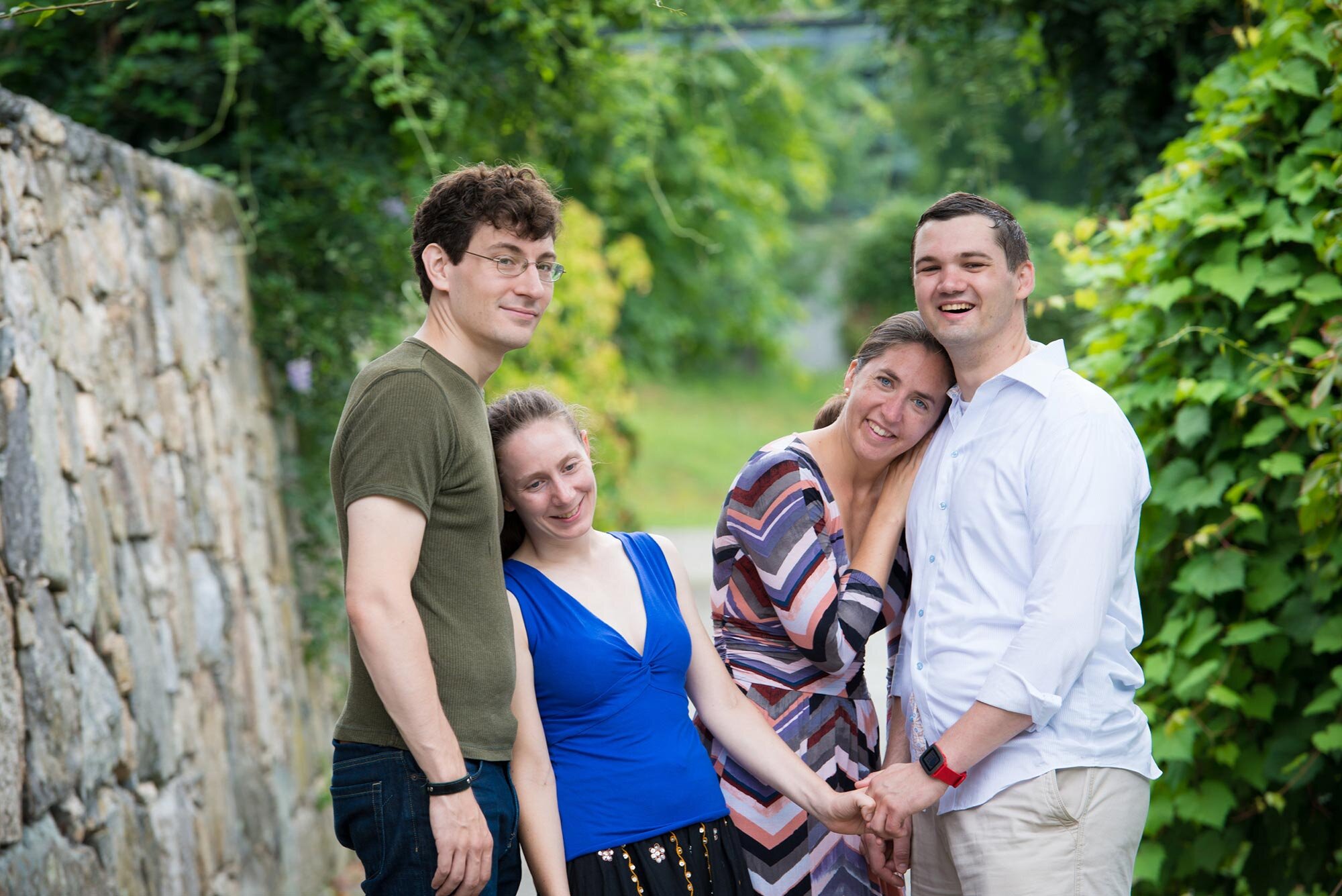 Family of four adults hug next to stone wall in Boston park Michelle Schapiro Photography