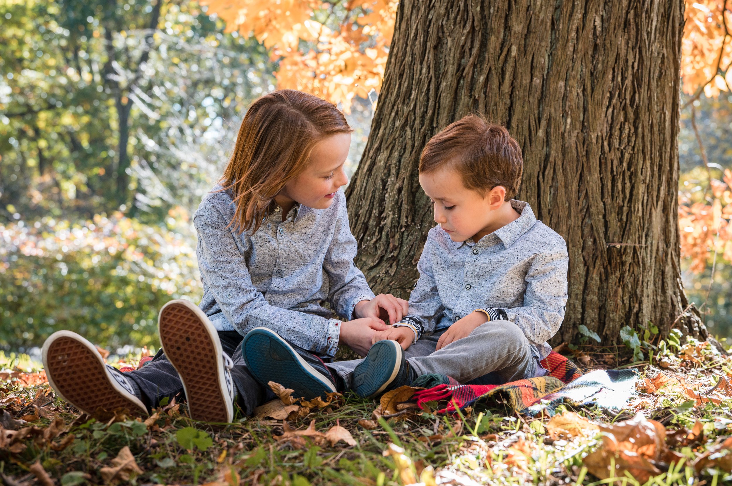 Younger siblings play in the fall leaves in New England by family portrait photographer by Michelle Schapiro Photography
