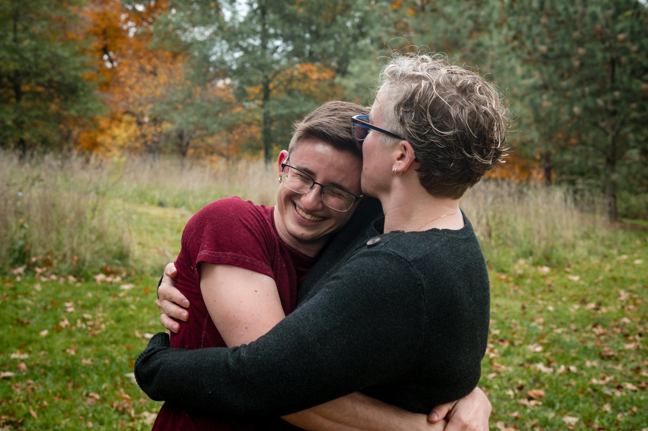 Queer couple embraces in the park in New England fall foliage by lesbian photographer Michelle Schapiro