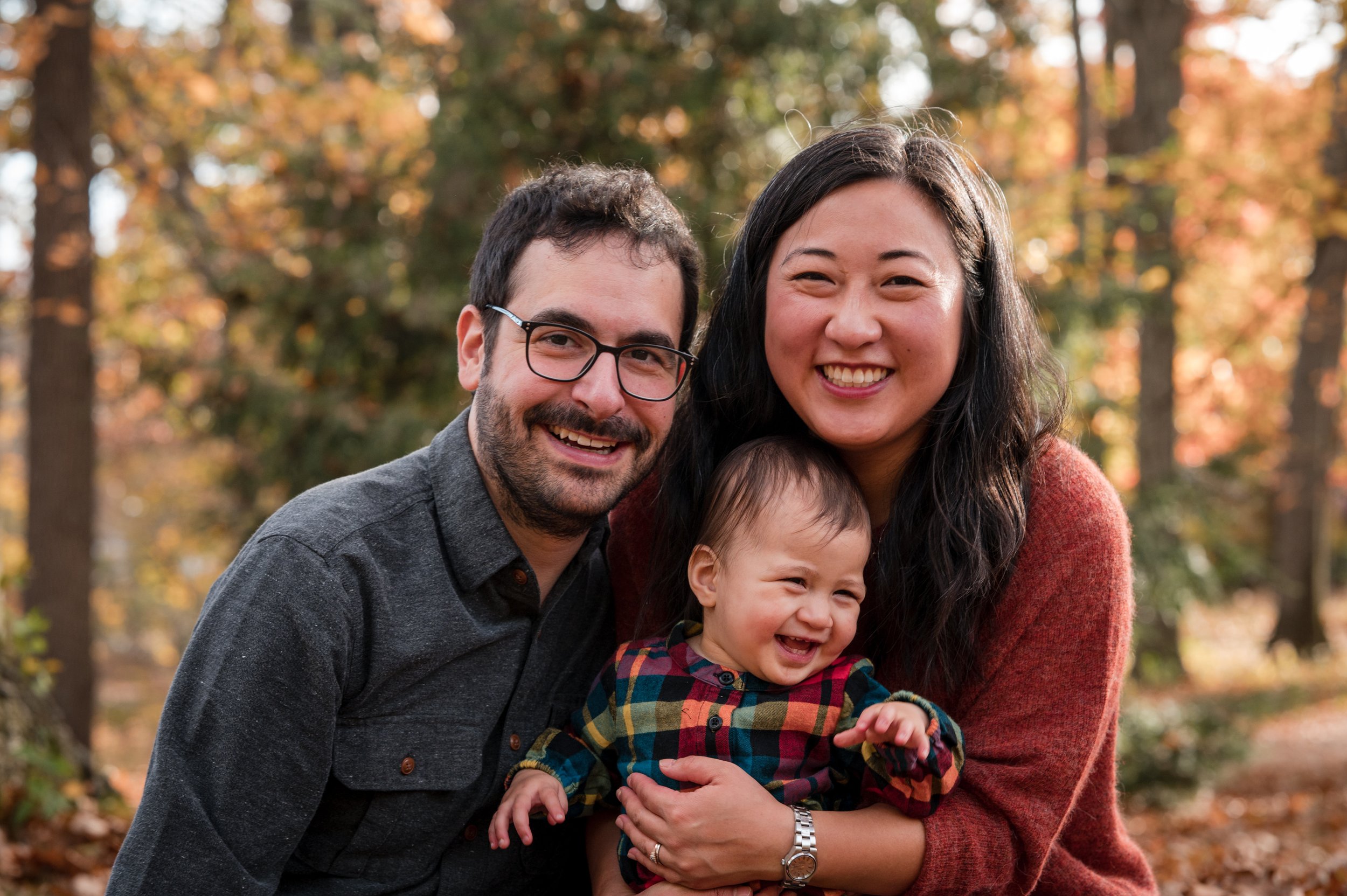 smiling mom and dad with toddler in new england fall park boston-based michelle schapiro photography
