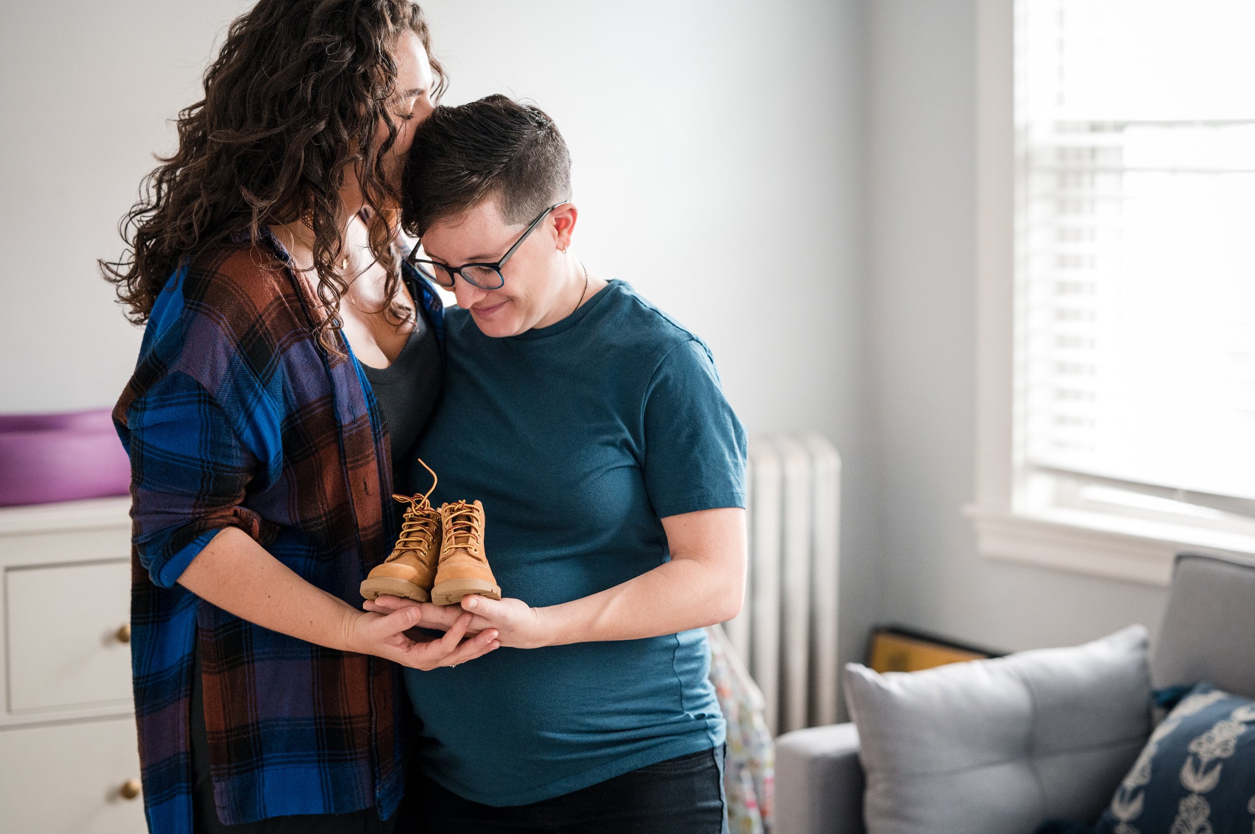 Expectant parents embracing each other during at-home portrait session by family photographer michelle schapiro