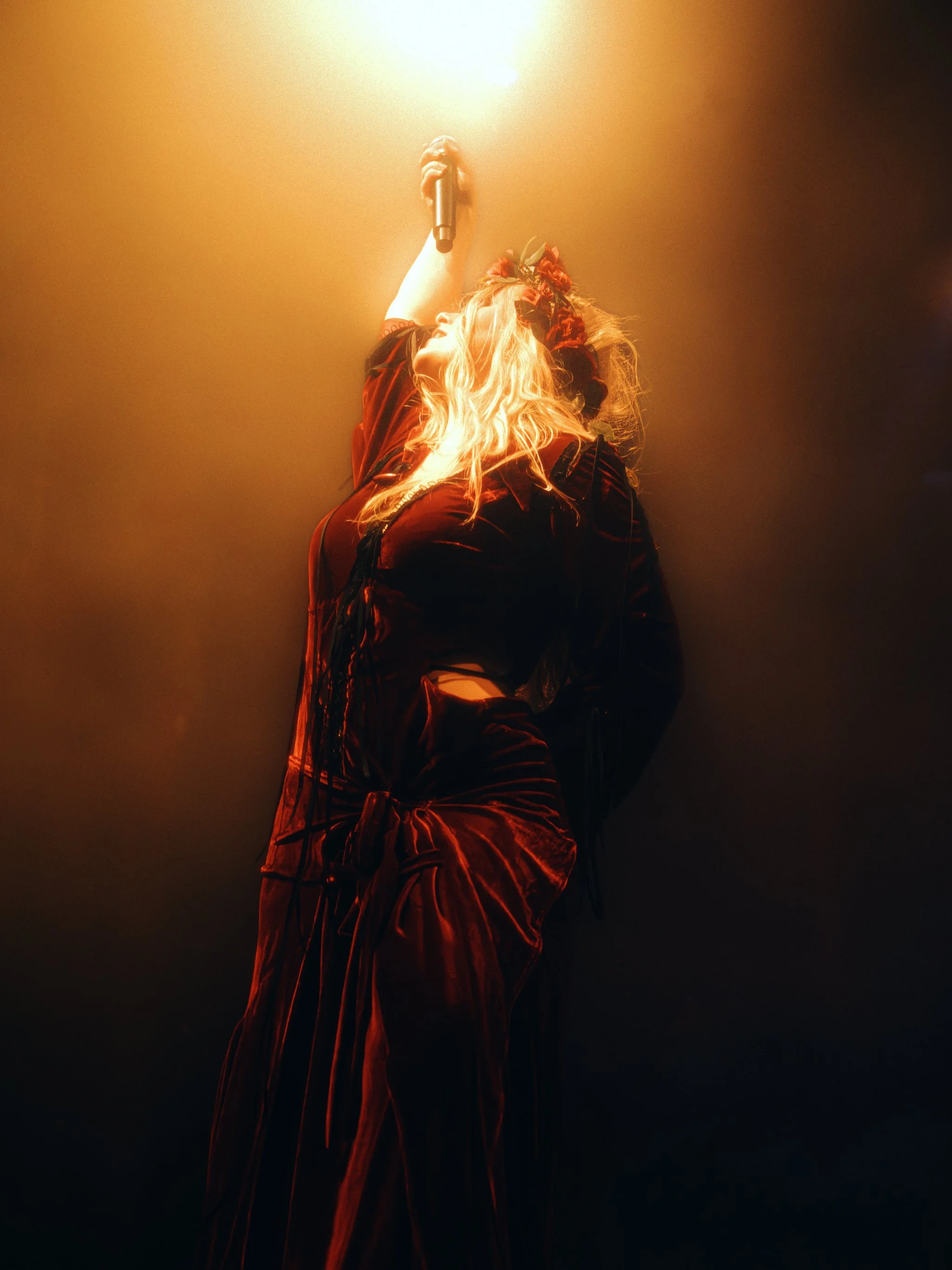 Paris Paloma reaching the mic overhead in a cloud of amber smoke