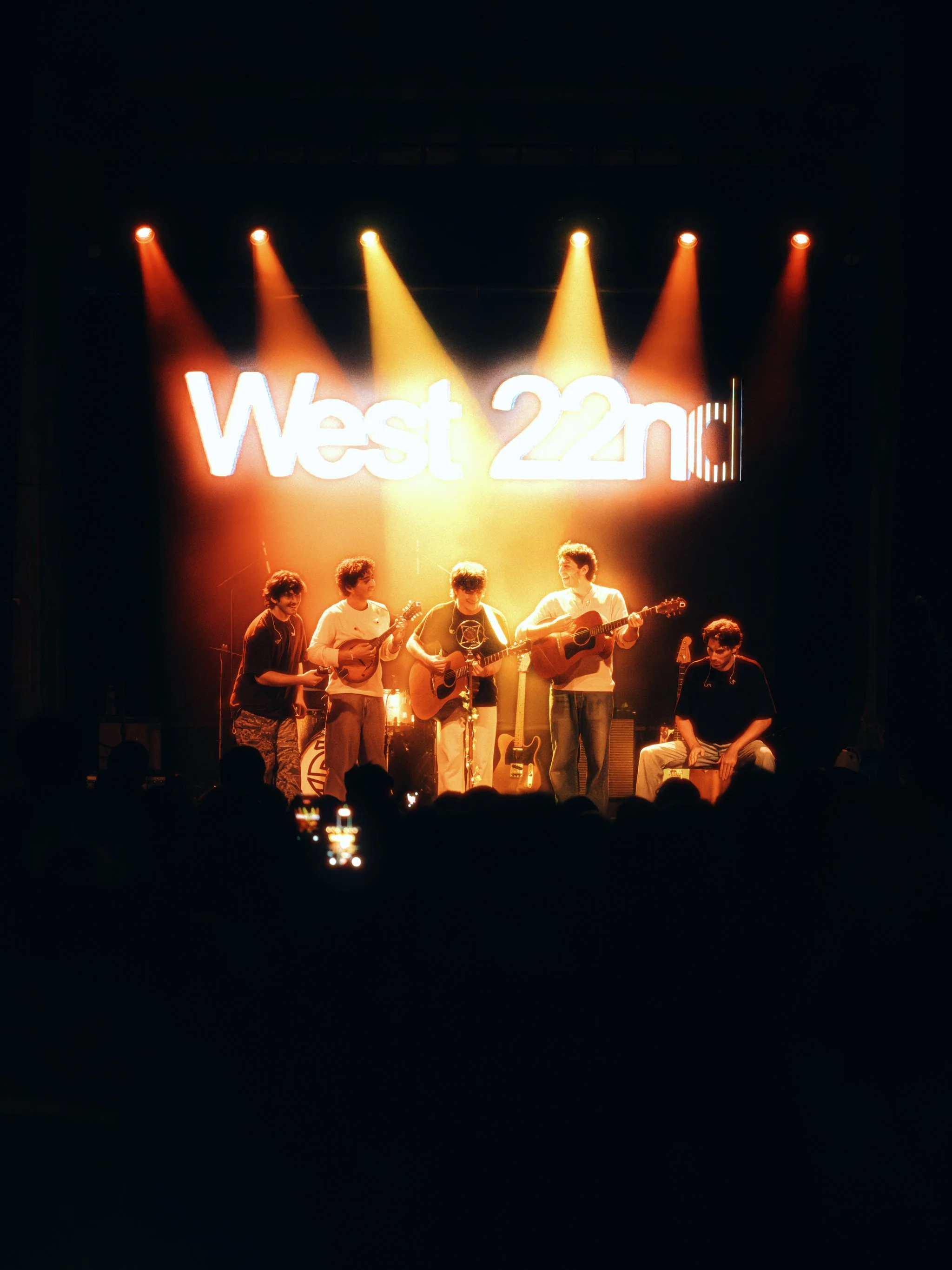 West 22nd lined up across the stage under six spotlights with their sign lit behind them