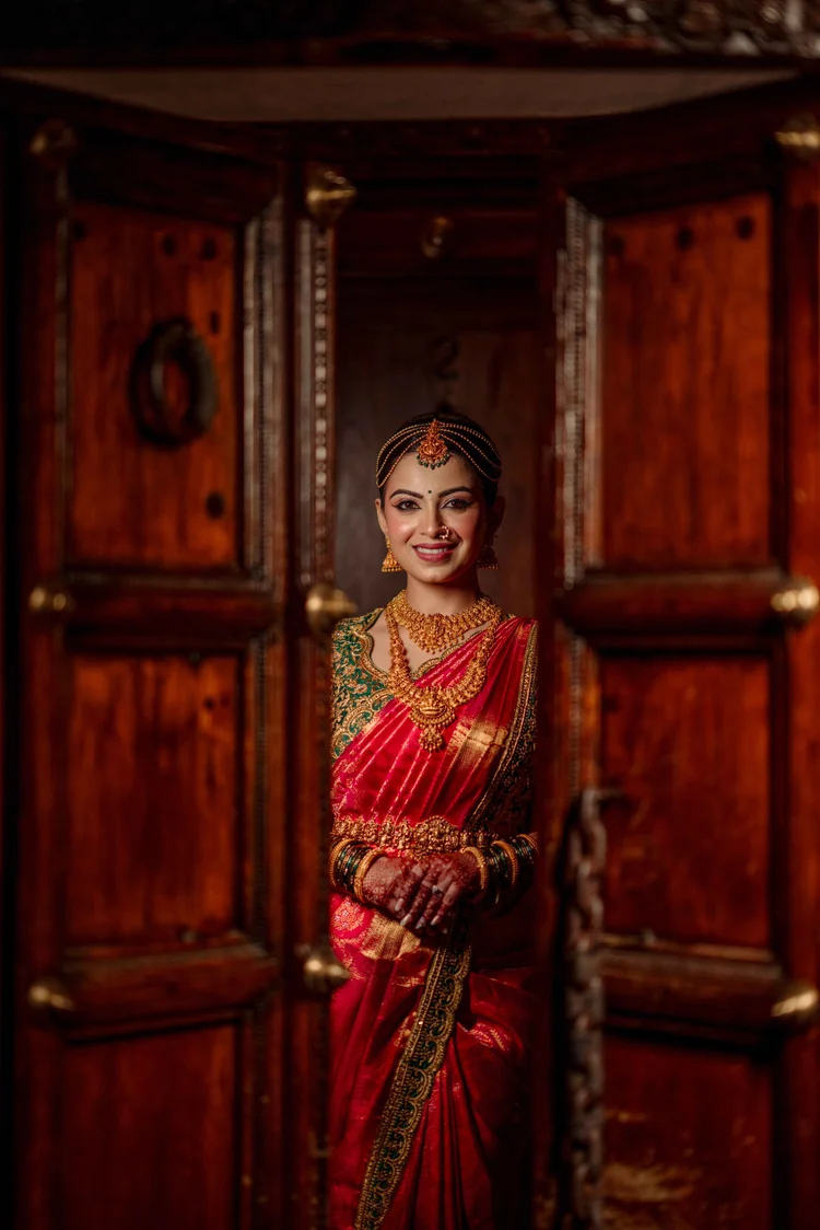 Bride in a red saree in a wooden doorway