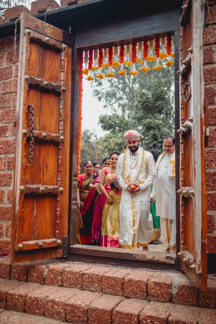 Groom framed by carved wooden doors as he walks in