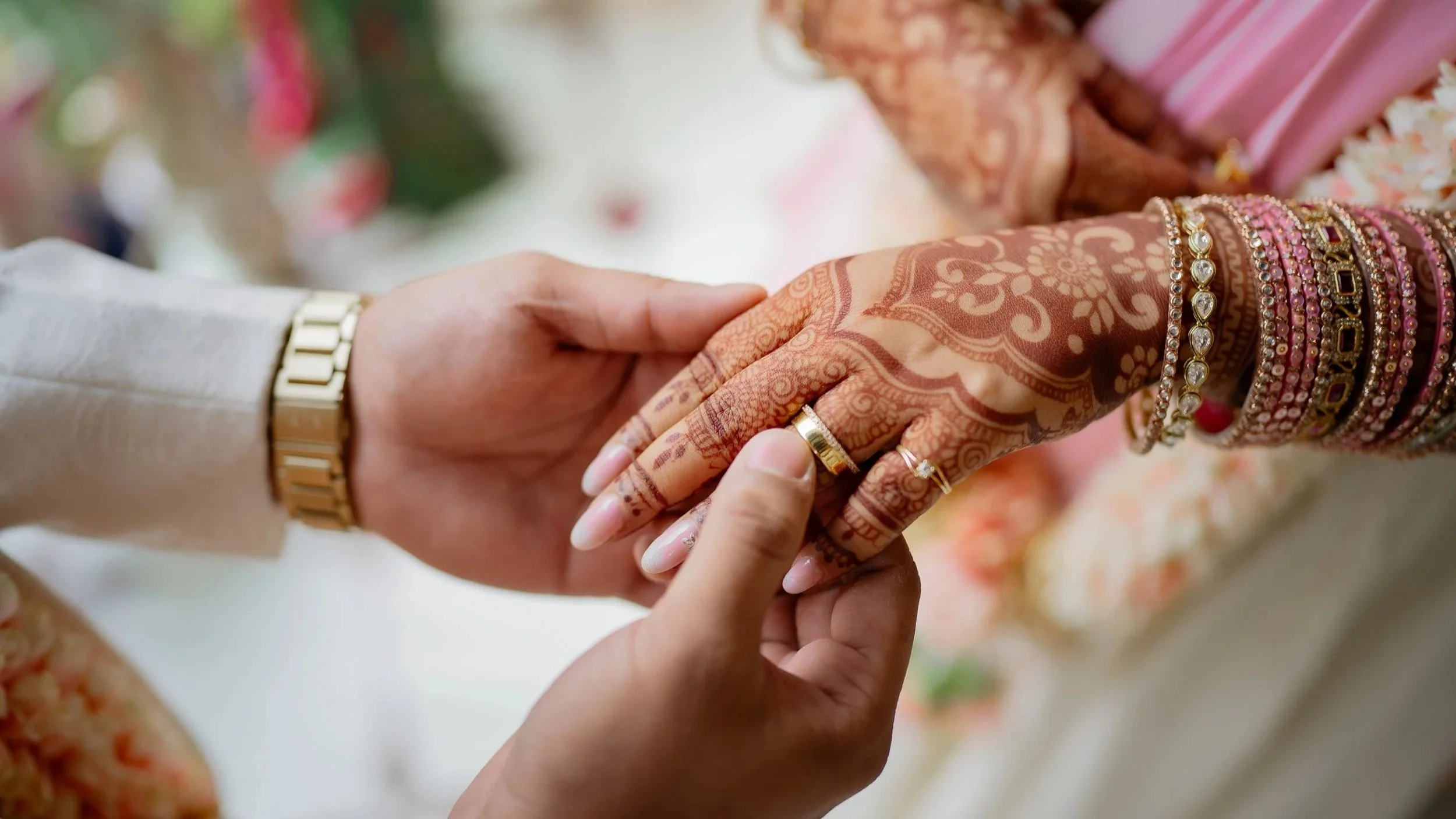 Groom placing engagement ring on bride's mehndi-adorned hand during Indian engagement ceremony, captured by Shutter Clicks Photography