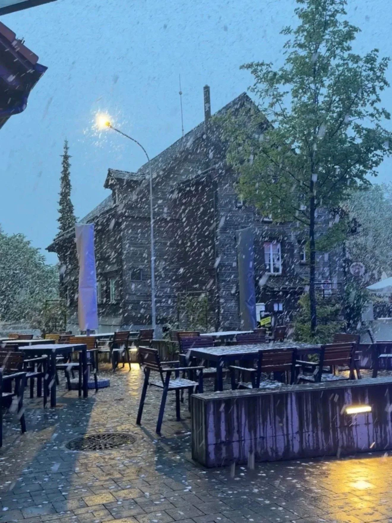 Snow falling over tables and chairs early in the morning in St. Gallen, Switzerland.