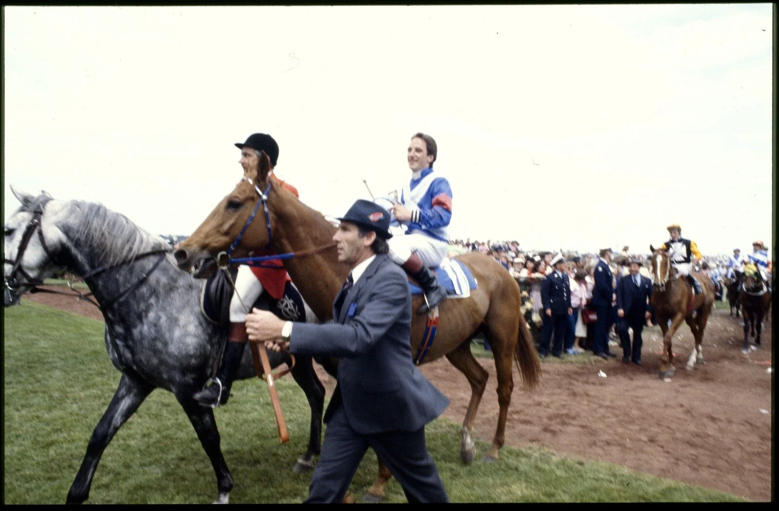 Ellis, R. (1983). [Clerk of the Course Leading 1983 Melbourne Cup Winning Horse, Kiwi and Jockey, Jim Cassady into the Mounting Yard] [picture] / Rennie Ellis., Rennie Ellis Collection. Spring Racing Carnival, Victoria$$QRennie Ellis Collection. Spring Racing Carnival, Victoria. Source: State Library of Victoria.