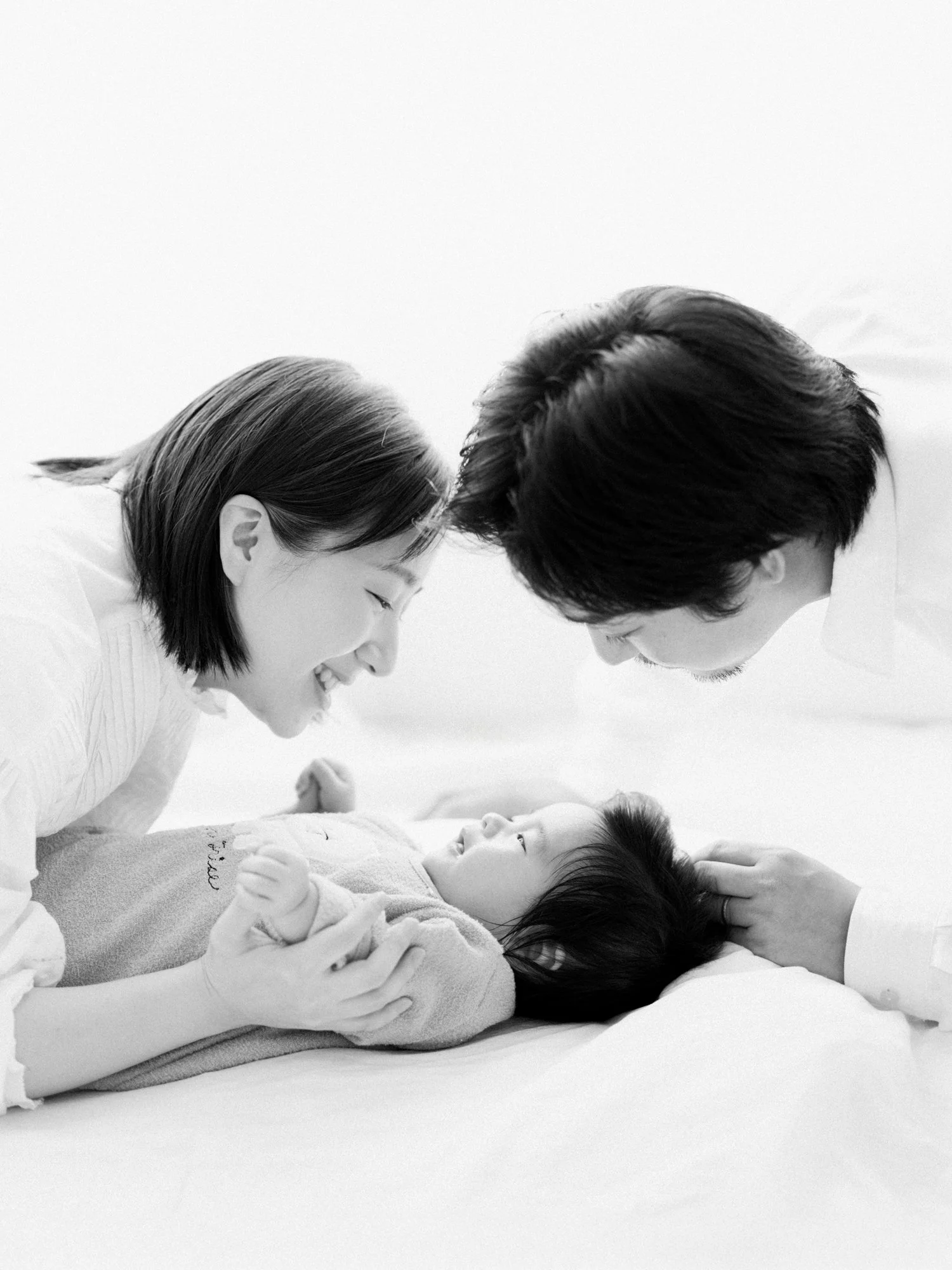 赤ちゃんと両親の家族の人々が見つめ合い、優しく触れ合う温かい瞬間を捉えた白黒写真