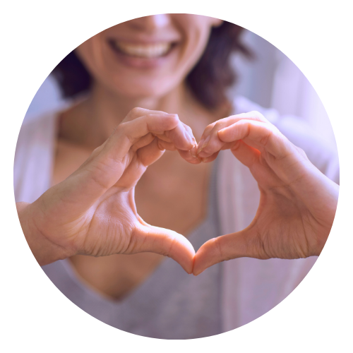 woman smiles and holds her fingers in a heart shape