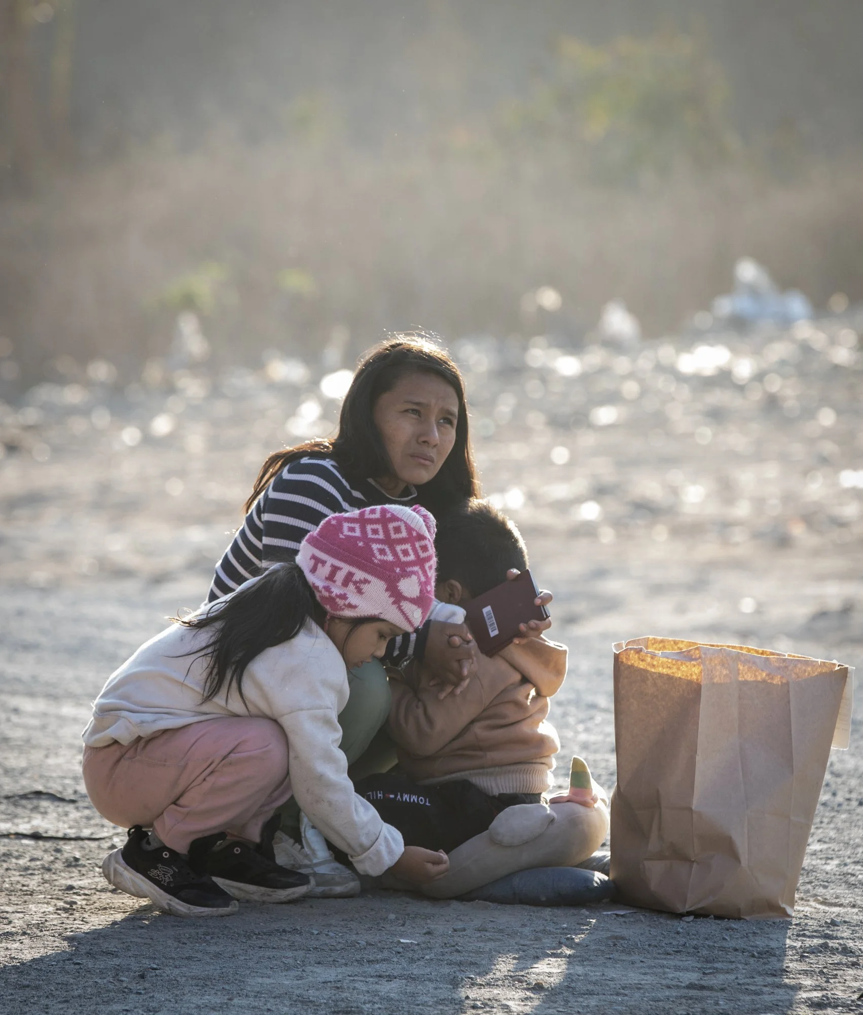 A Peruvian mother breastfeeds her three-year-old son while her five-year-old daughter plays with rocks after they were picked up by U.S. Border Patrol agents between the two border walls on Monday, Jan. 20, 2025 in San Ysidro, California. 