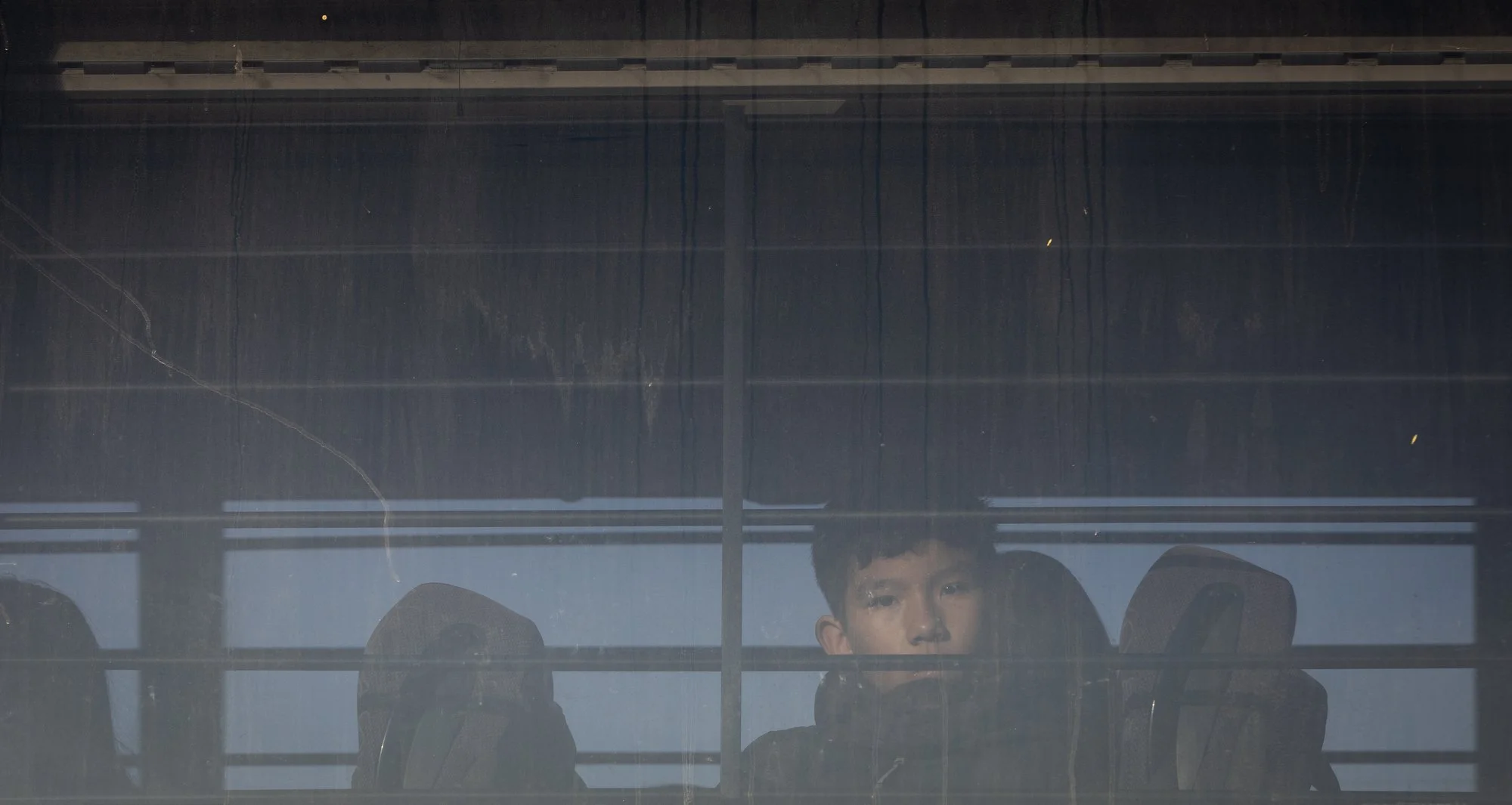 A nine-year-old boy from Colombia peers out of a bus before being on Monday, Jan. 20, 2025 in San Ysidro, California. 