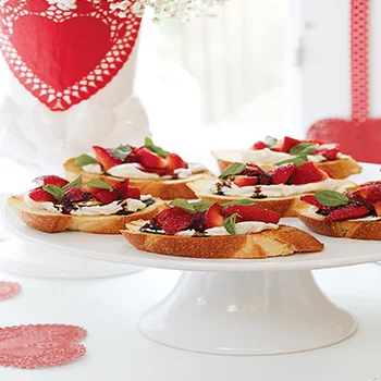 Nice Nibbles Strawberry & Goat Cheese Bruschetta: In a small sauce- pan, bring 1⁄2 cup of balsamic vinegar to a simmer over medium low heat. Simmer for 8 minutes, or until reduced by half. Cool to room temperature. Heat a grill pan over high heat. Brush 12 slices ciabatta or other Italian bread with olive oil. Grill bread 3 minutes per side, or until browned. Spread grilled bread with goat cheese. Top with strawberries, add salt and pepper, and drizzle with balsamic syrup. Sprinkle with basil. Makes 12 servings.