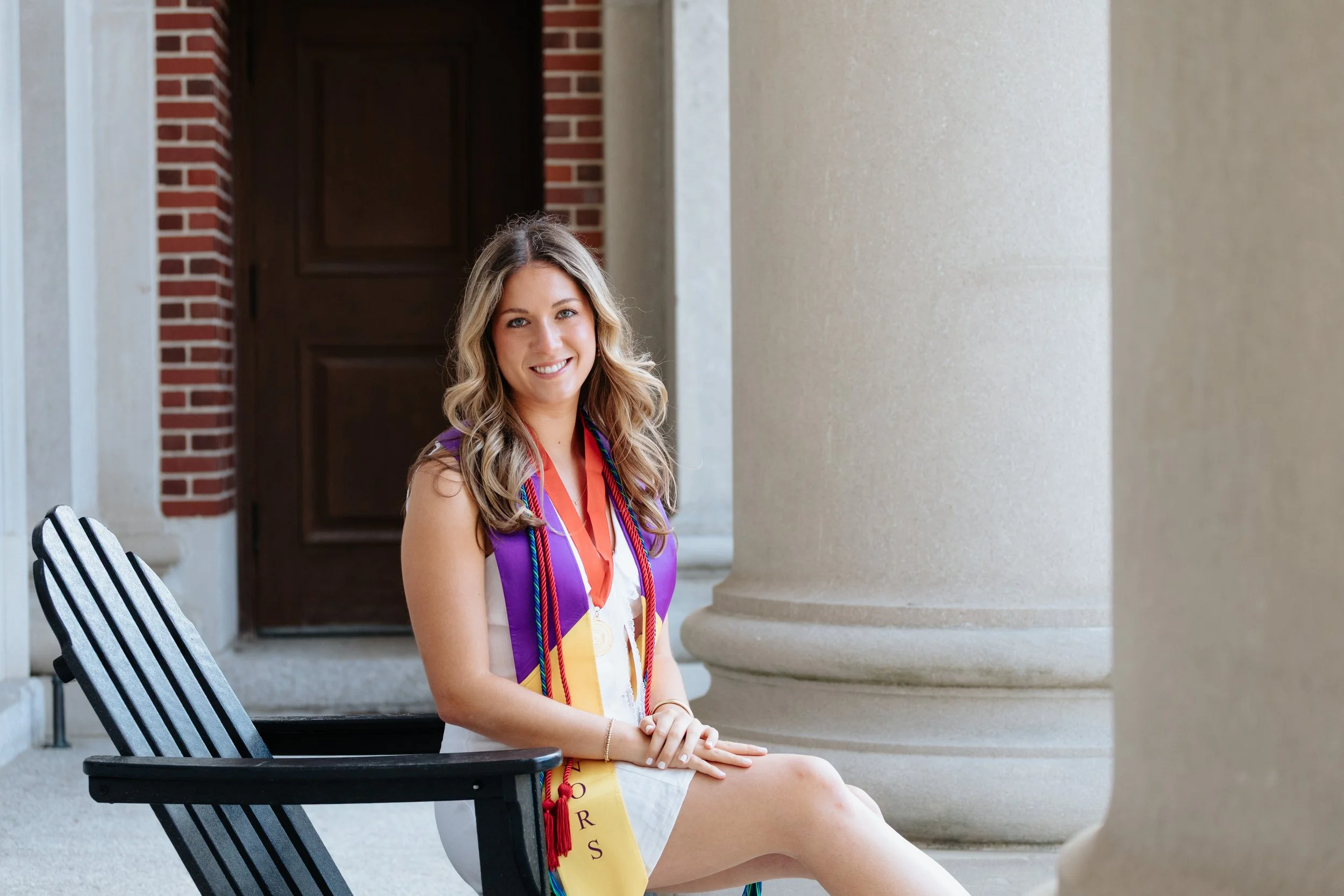 Portrait of Holy Cross graduating senior on chair during cap and gown session in Worcester.