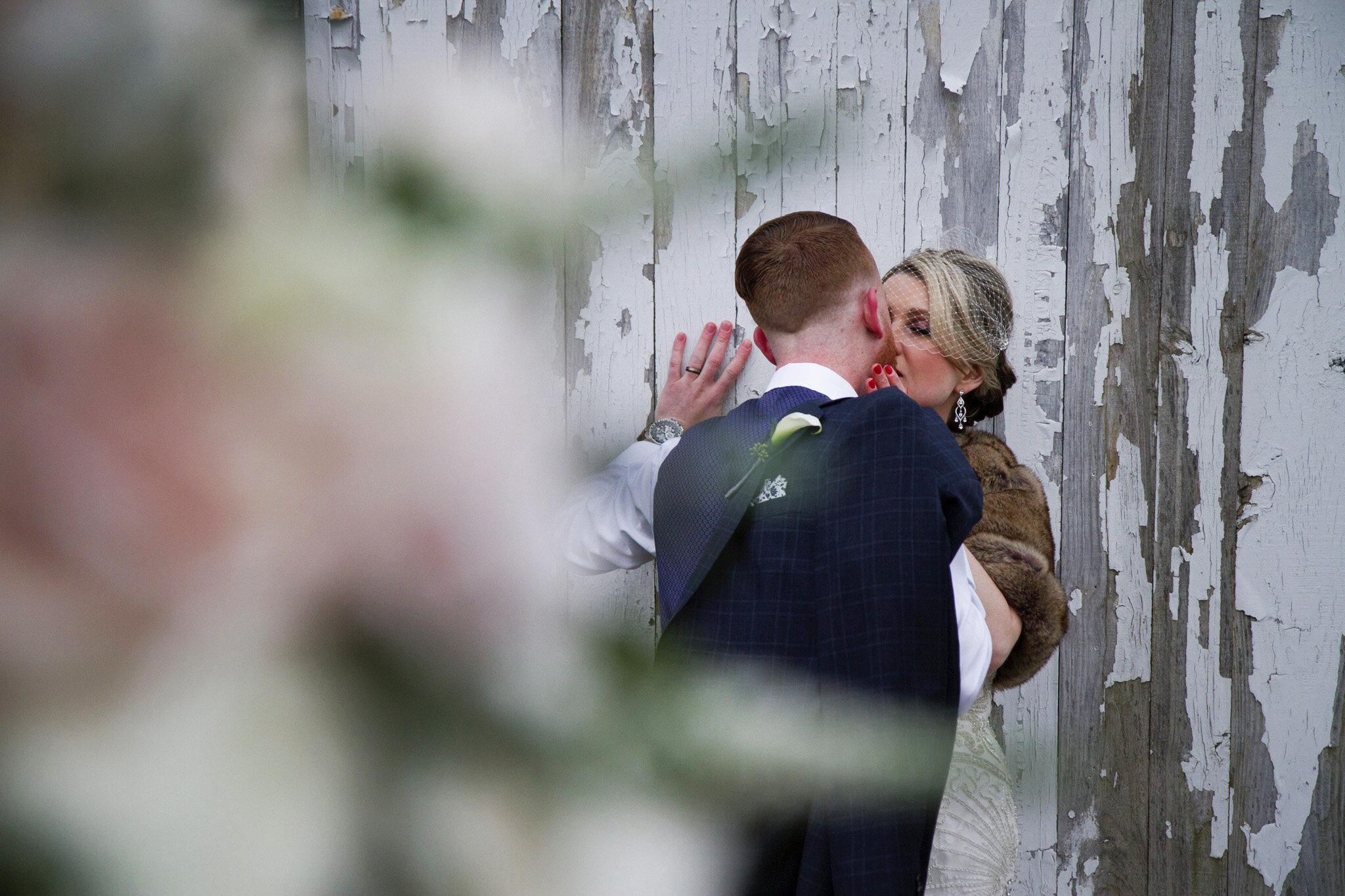 bride-groom-kiss-against-rustic-barn.jpg
