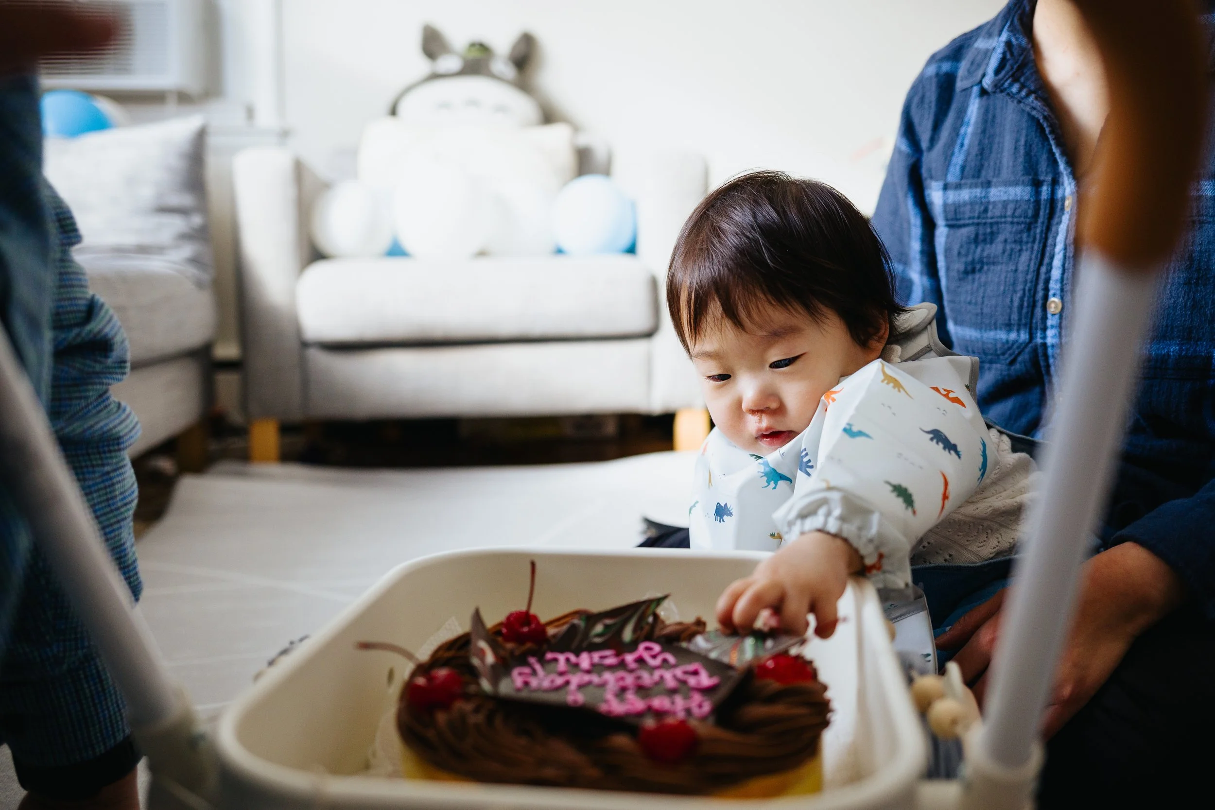 Baby reachin to birthday cake during lifestyle family session in Grafton, MA.