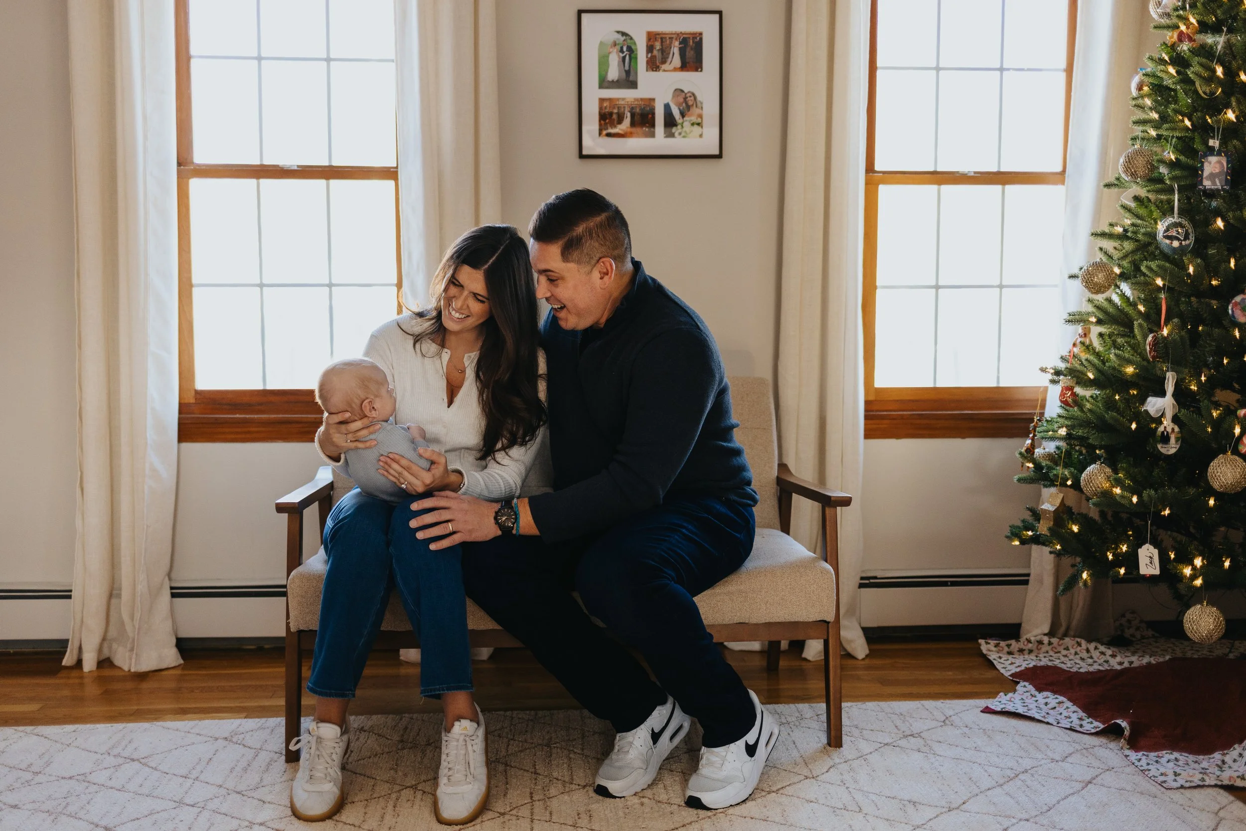Family playing with baby next to a Christmas tree during a lifestyle family portrait session in Lancaster MA.