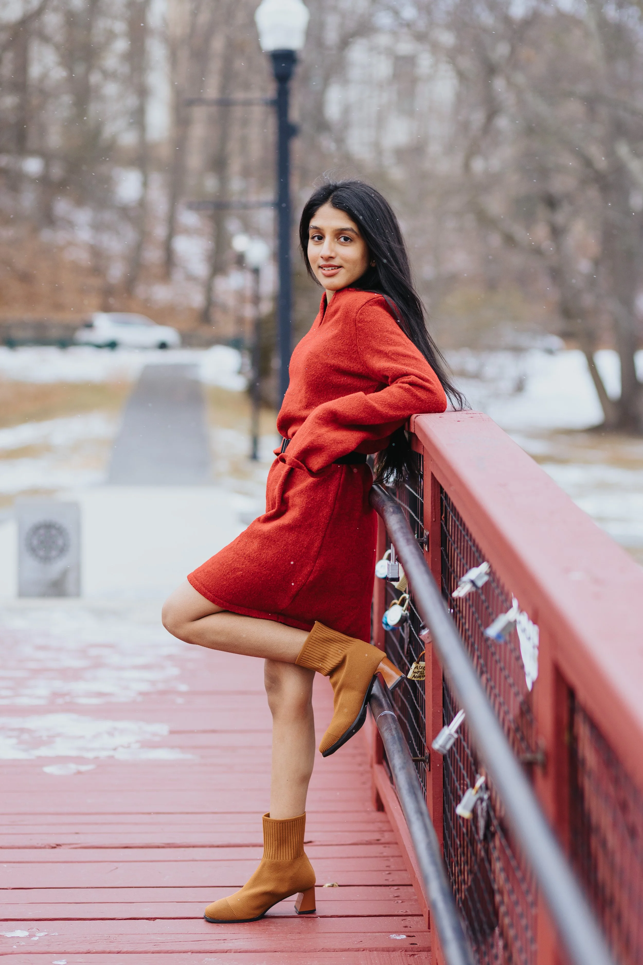 Snowy winter senior portrait of girl in red jacket on the bridge of Elm Park in Worcester.