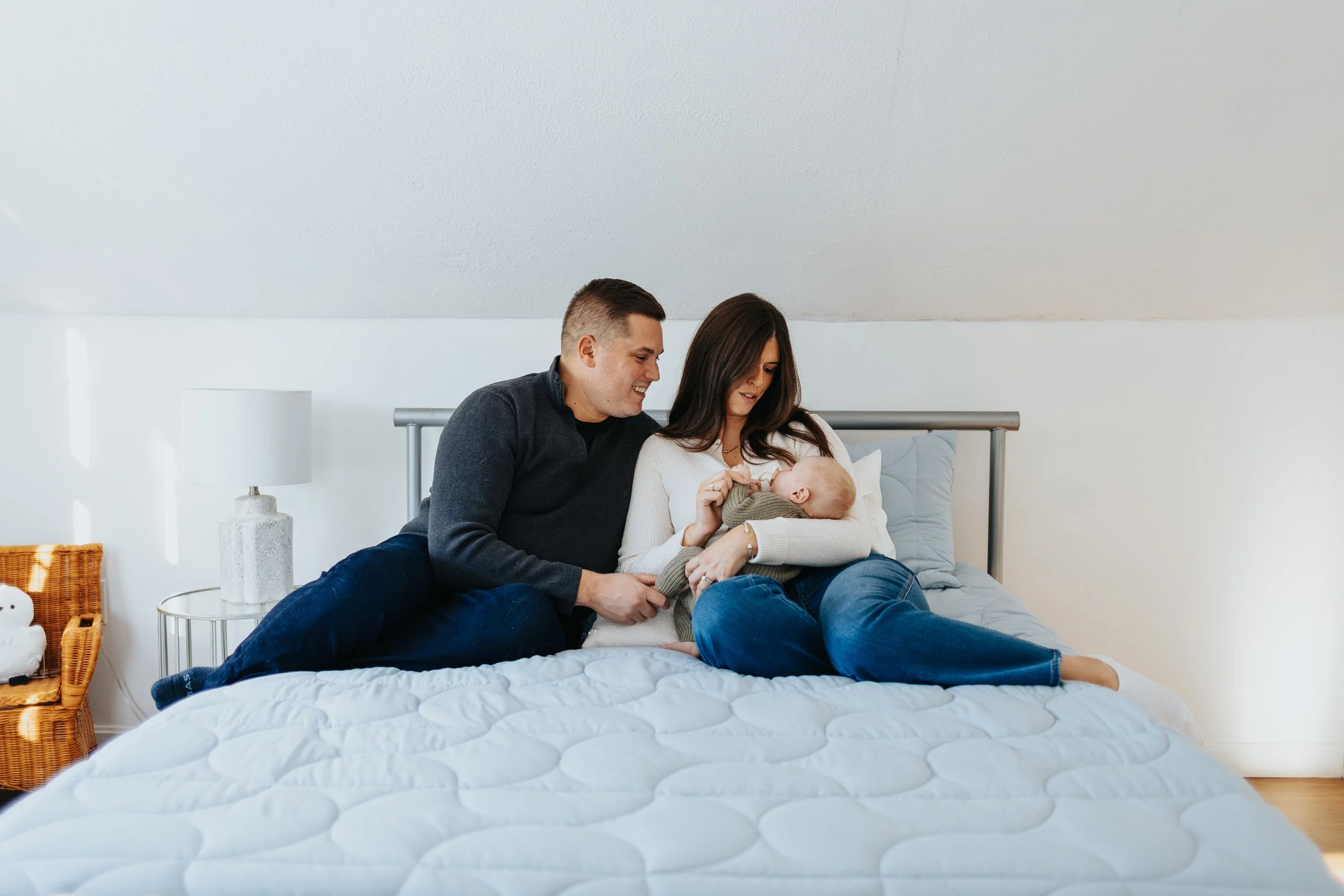 Family sitting on bed during a lifestyle family portrait session in Lancaster MA.