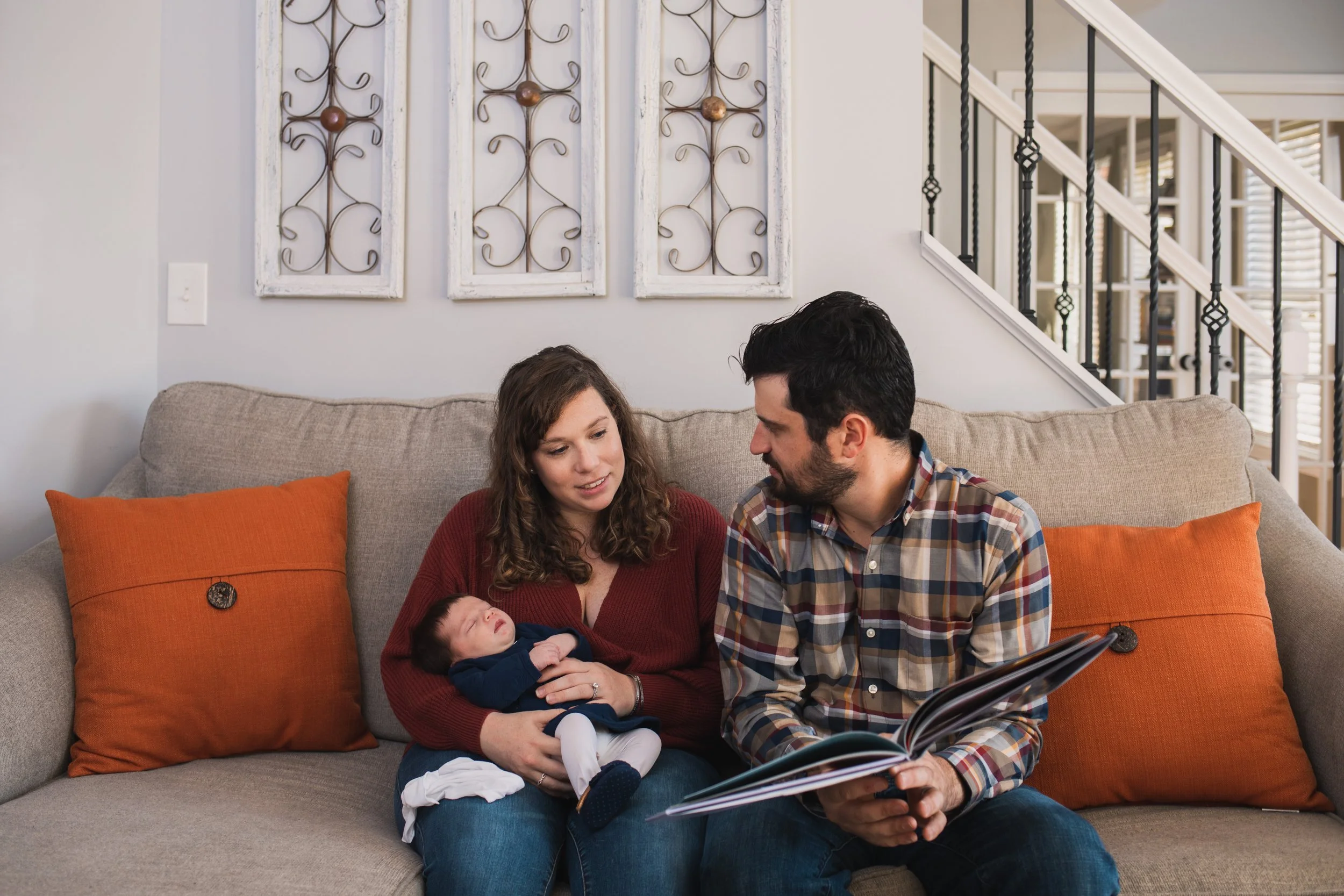 Lifestyle family portrait session of parents and newborn reading on couch in Holden by Worcester photographer Tom Godfrey Photography.