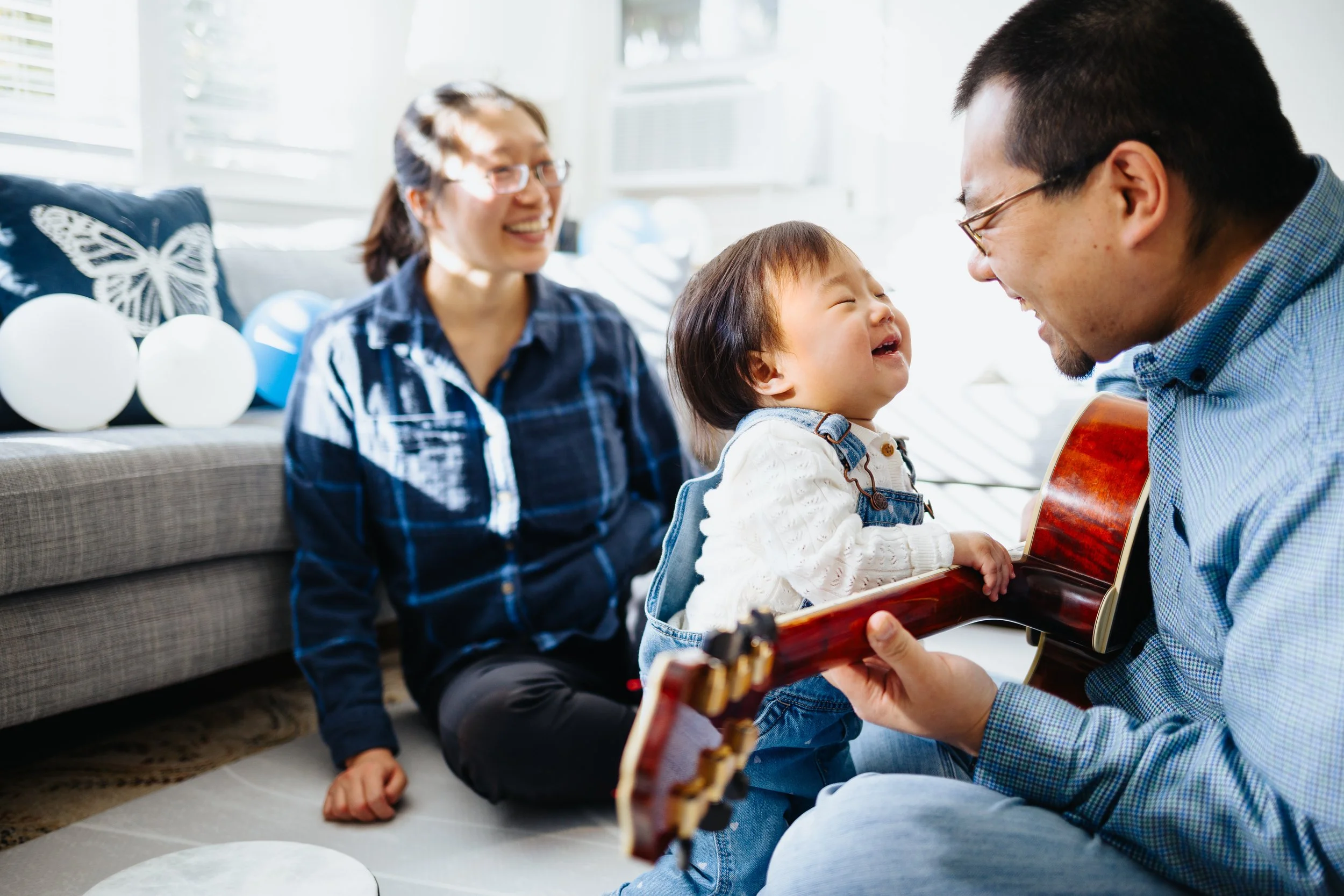 Happy baby listening to her dad play guitar during family session in Grafton.