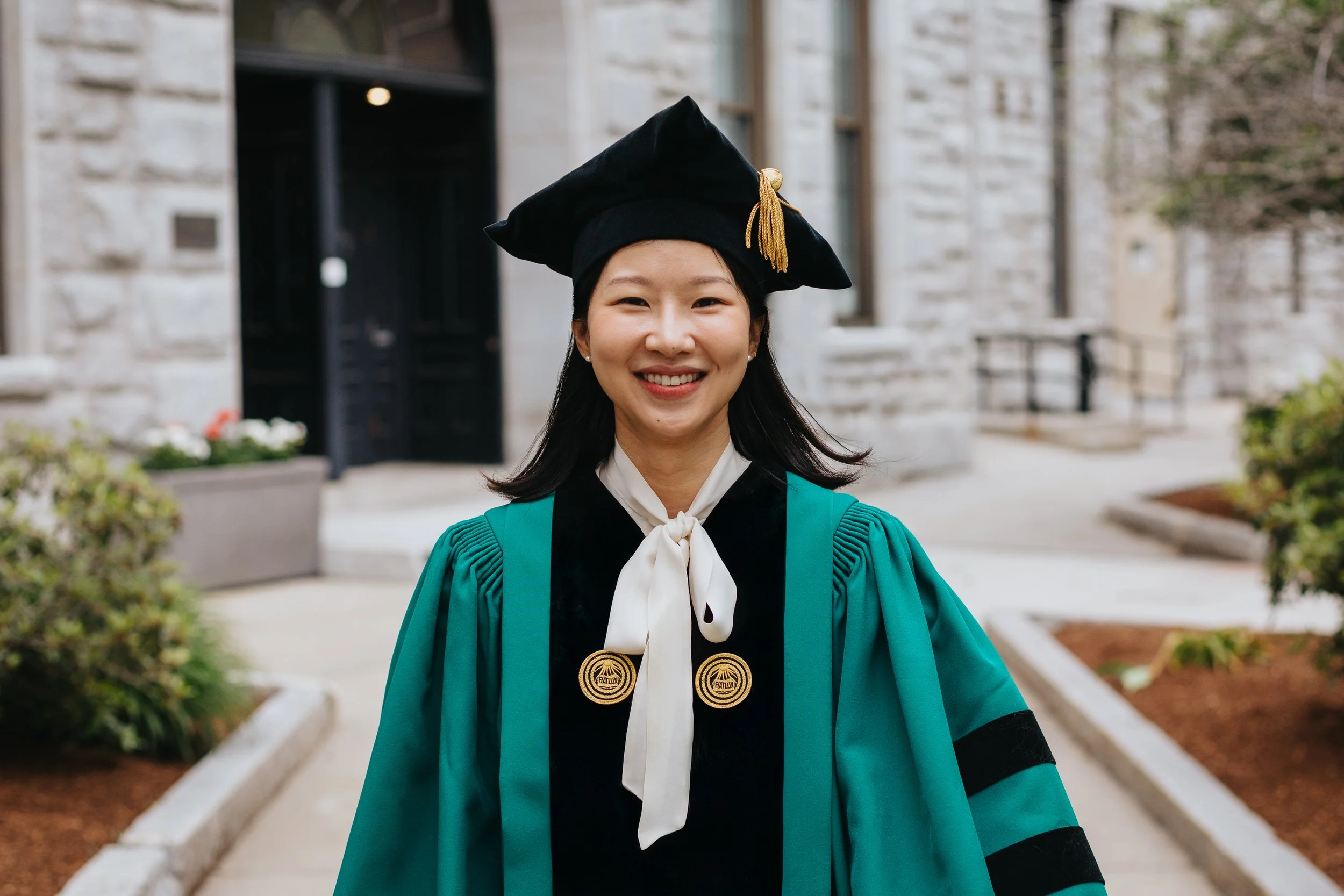 Clark University graduate in regalia during cap and gown session in Worcester.