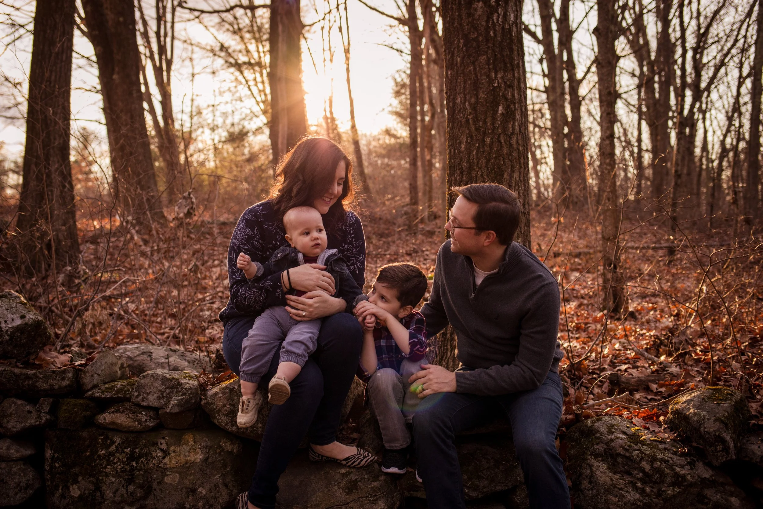 Relaxed family portrait of family sitting on wall during fall sunset at Moore State Park in Paxton, MA by Worcester family photographer Tom Godfrey Photography.