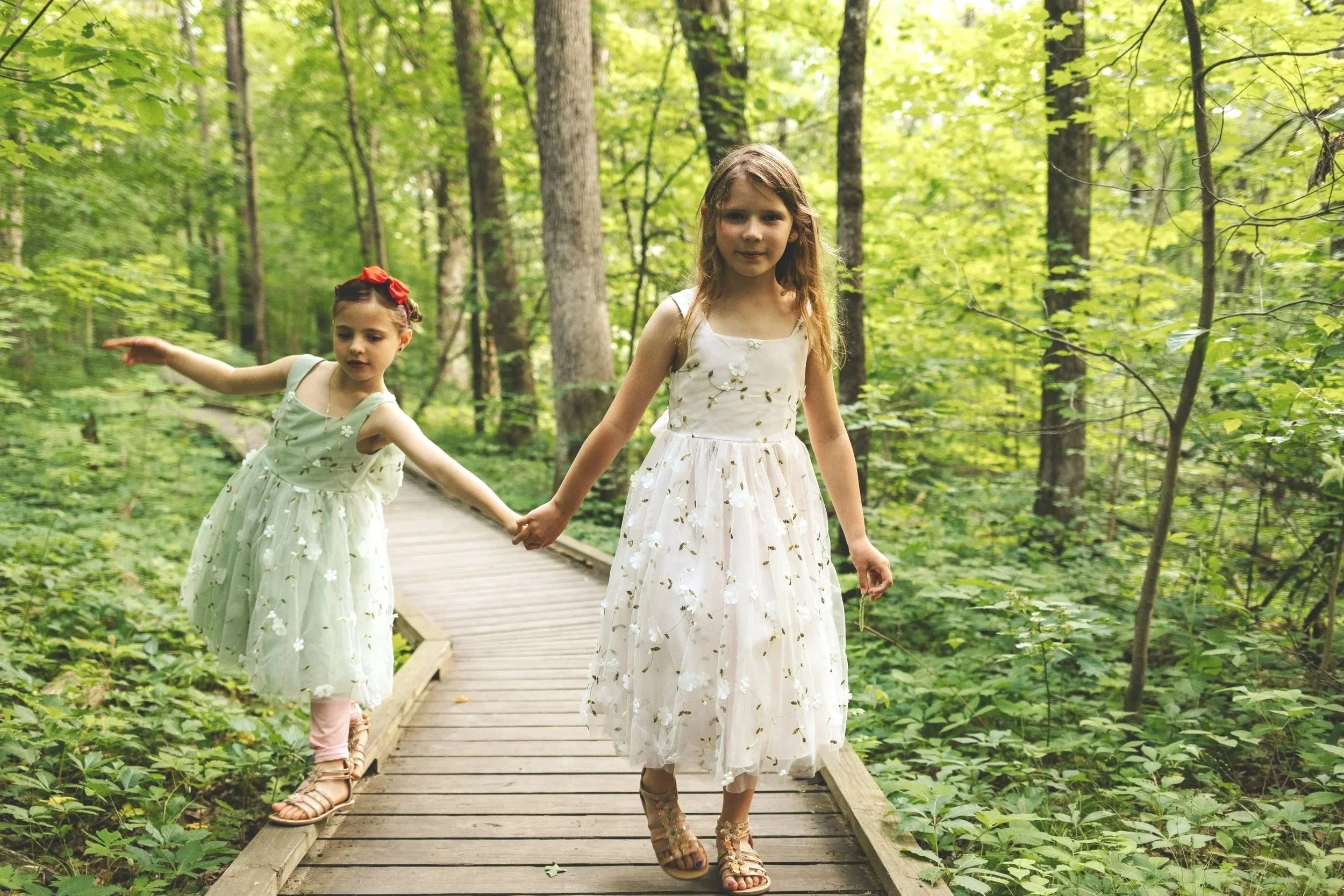 Casual family portrait of two girls walking on bridge in Acton Arboretum by Worcester photographer Tom Godfrey Photography.