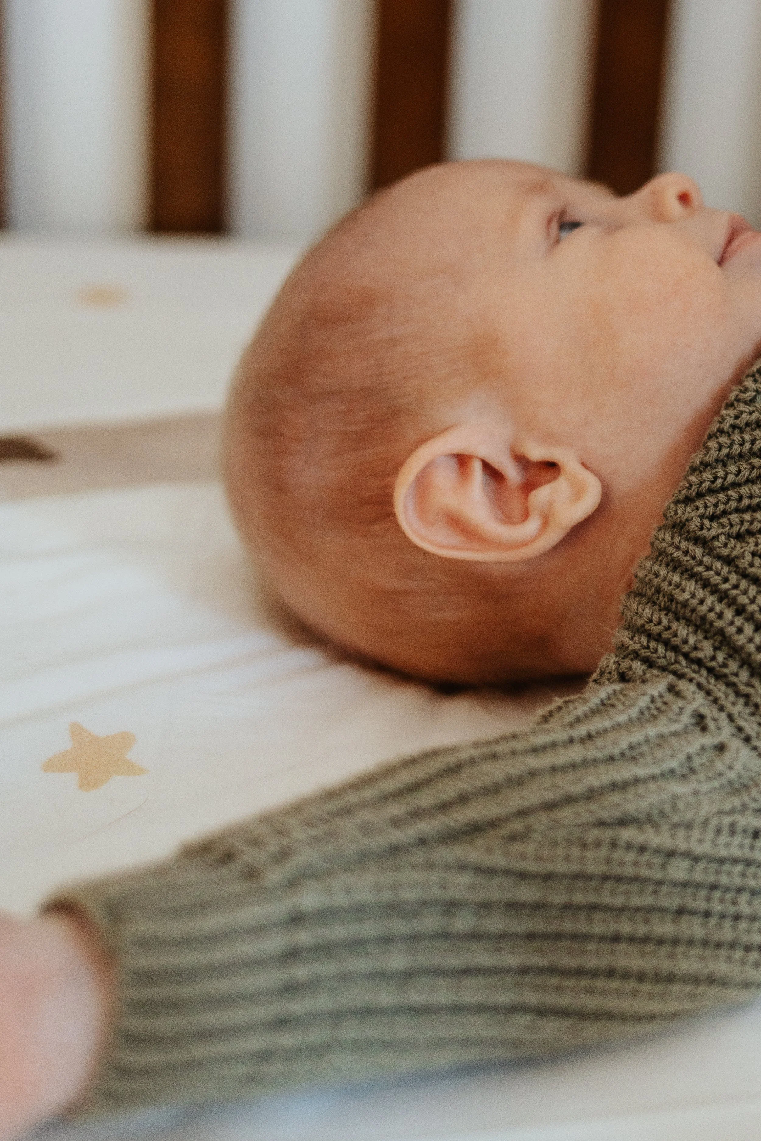 Detail photo of newborn ear captured during a lifestyle family portrait session in Lancaster MA.