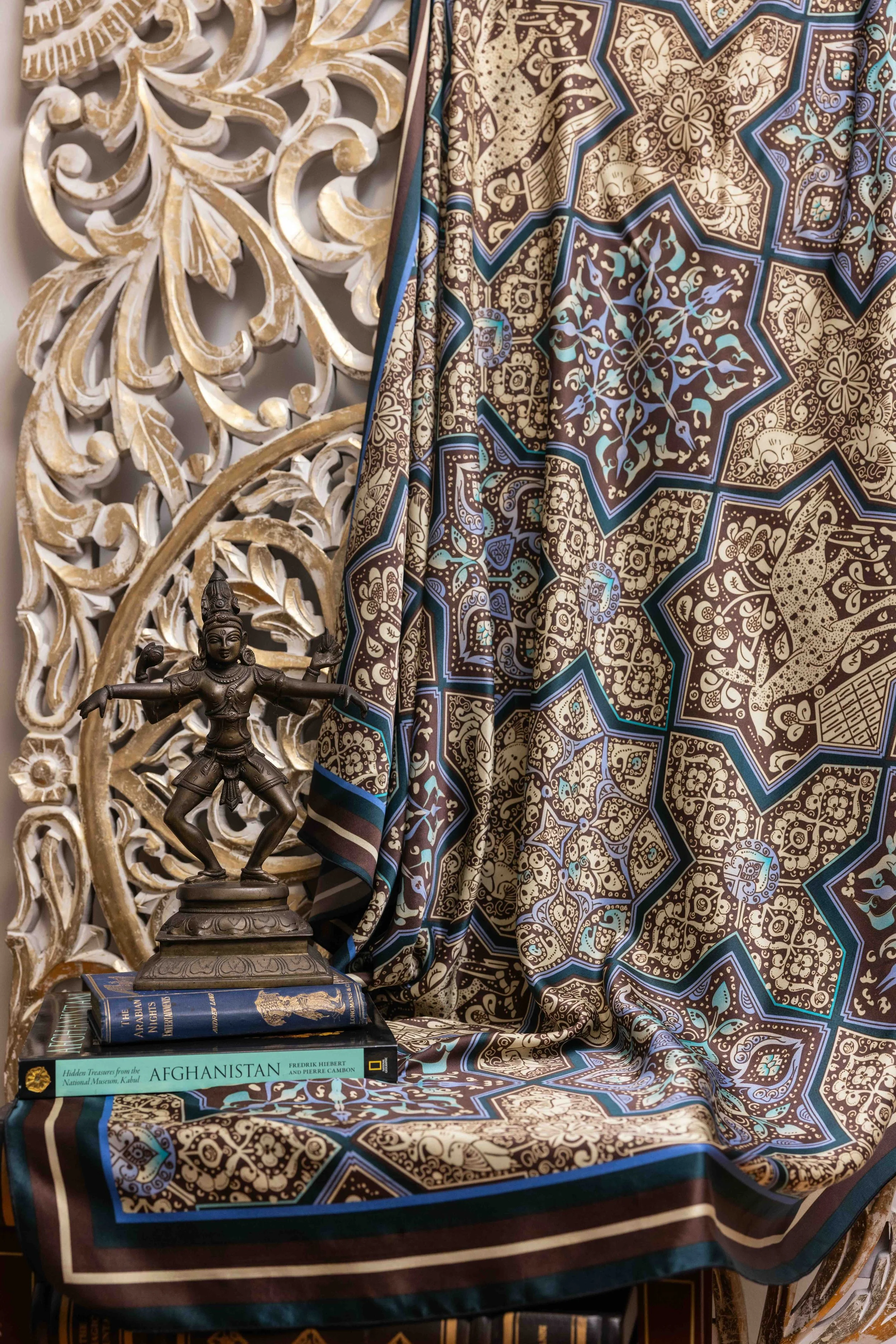 Books, Hindu sculpture, and patterned textile representing Ihsan Ishan Design’s educational stories exploring faith, art, design, and culture.