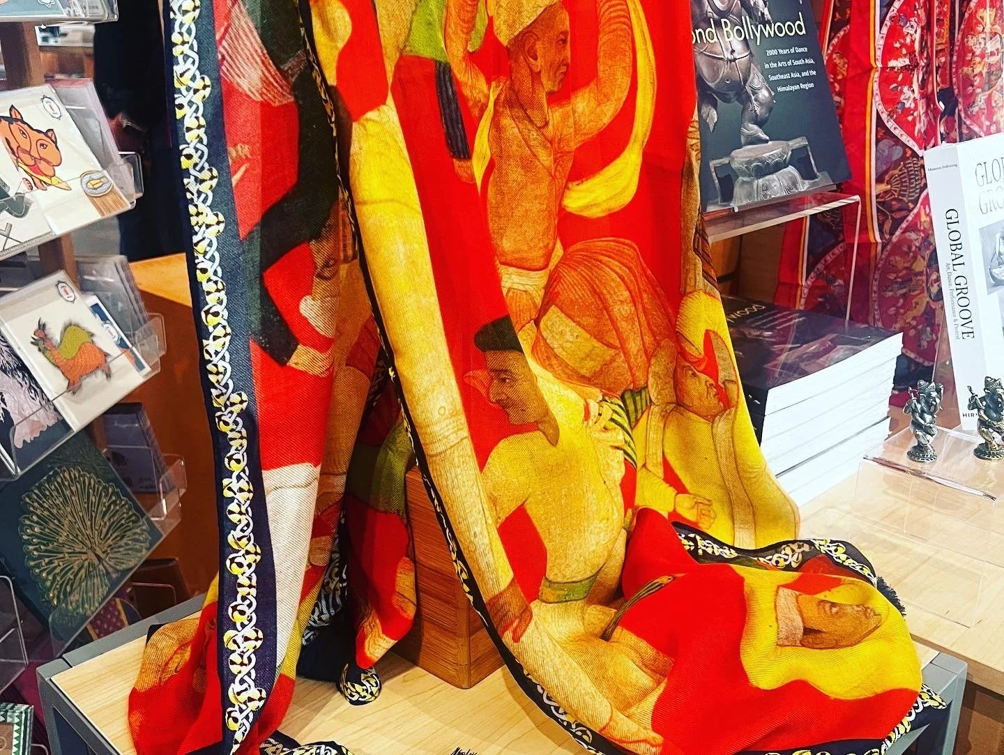 Detail of Sangeetha Kowsik’s Beyond Bollywood scarf displayed at the Asian Art Museum, featuring artwork inspired by the history and experiences of Indian Americans.