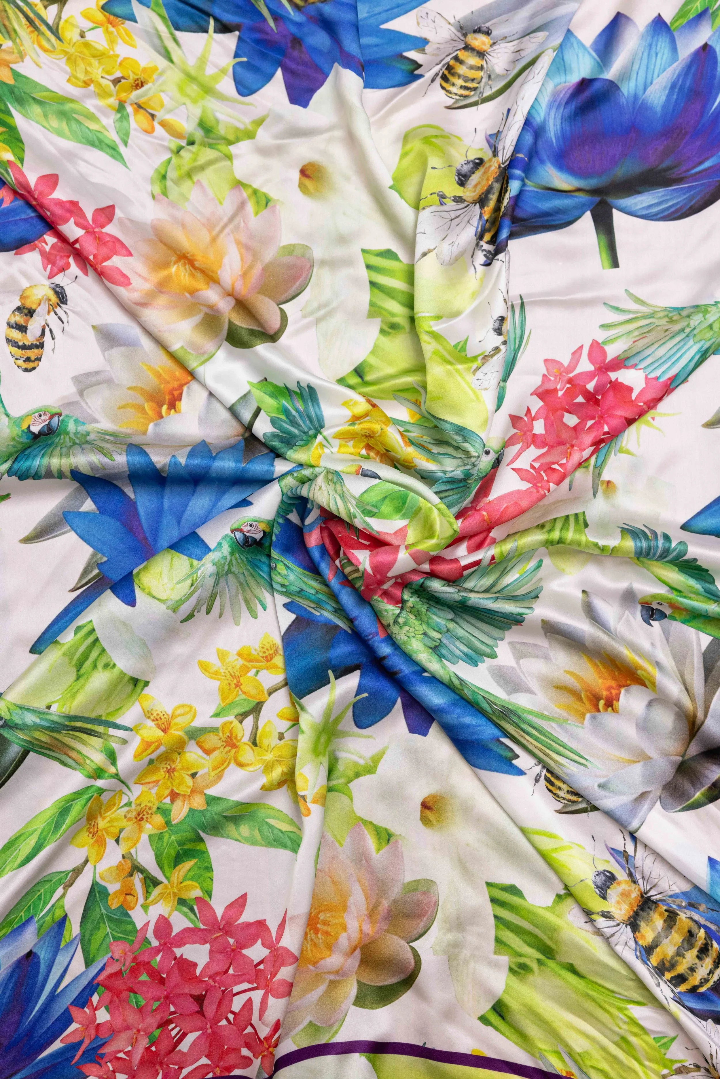 Detail of an Ihsan Ishan Design silk scarf featuring colorful botanical and bird motifs, showcasing luxury materials and craftsmanship.