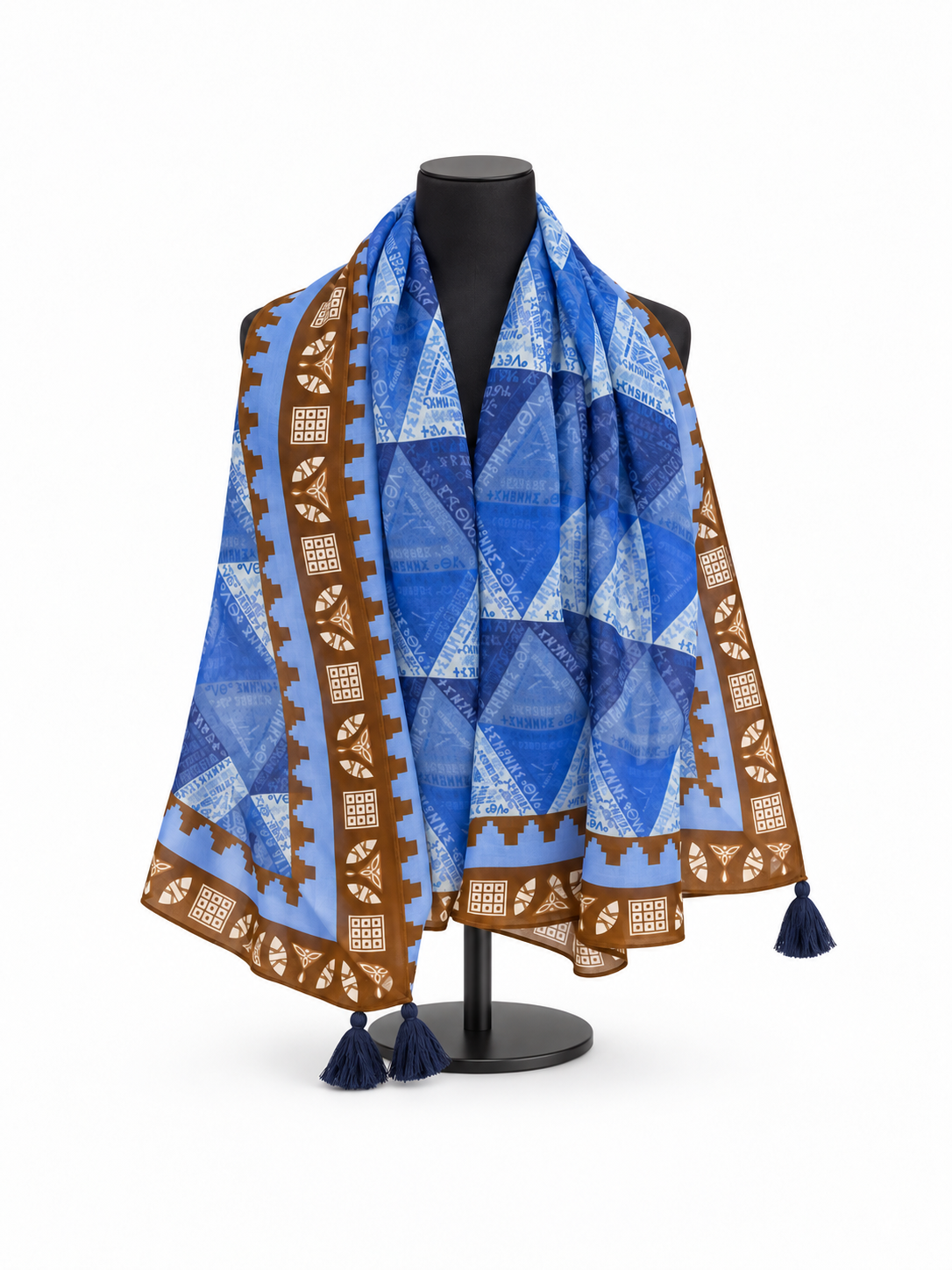 Draped Amazigh Tillei Abda “Always Be Free” scarf showing blue geometric pattern, Tifinagh script, decorative border and dark blue corner tassels.