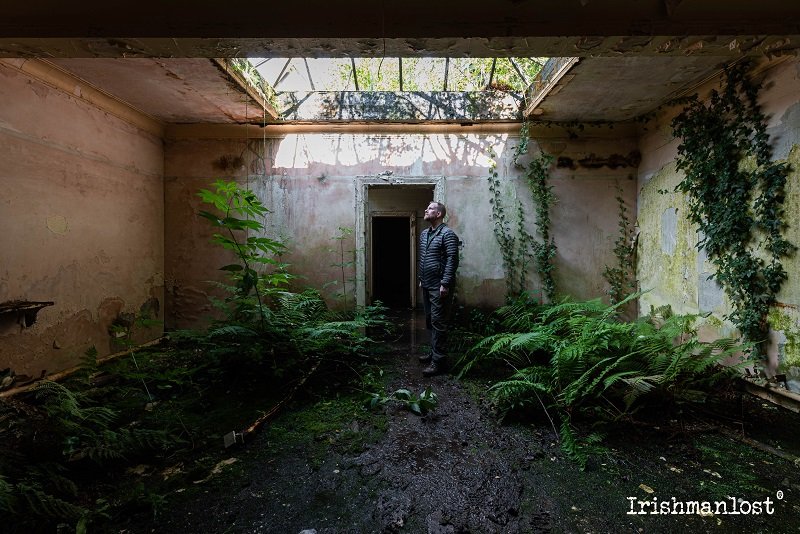 Irishmanlost inside carndhu house looking upto a ceiiling skylight in a overgrown room