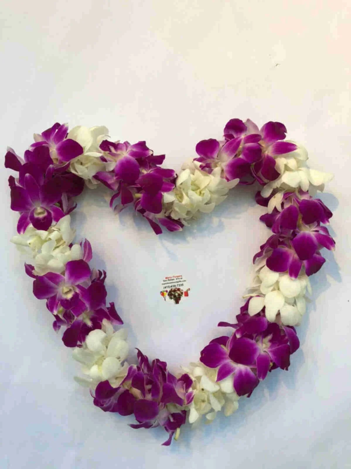Heart-shaped flower lei made of white and purple orchids against a plain white background.