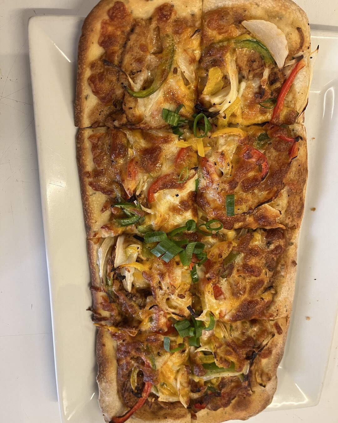 New!  Chicken Fajita Flatbread Seasoned grilled chicken multi color bell pepper onions our secret sauce cheddar and mozzarella cheese topped with green onions and a side of sour cream.  A little heat and filled with flavor.