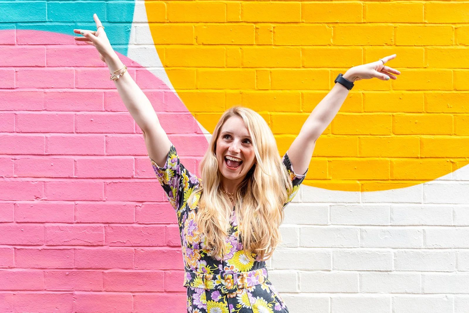 woman on a branding shoot stood in front of coloured wall smiling