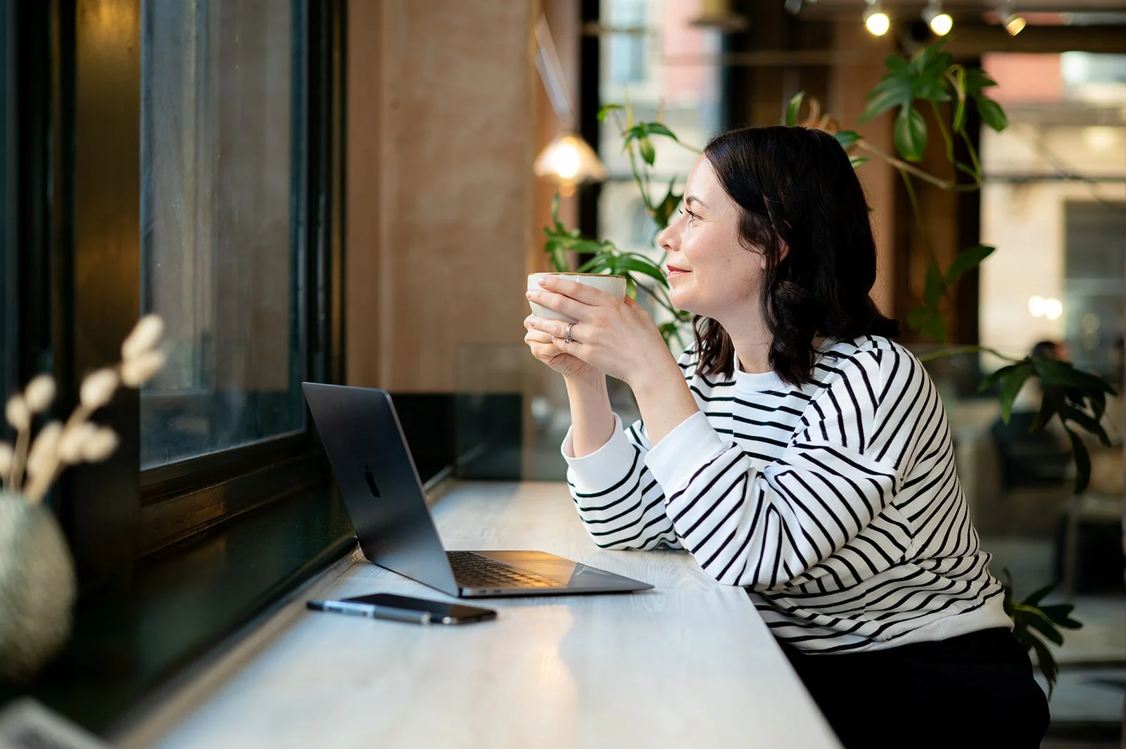 women sat  looking out of the window having a coffee whilst working