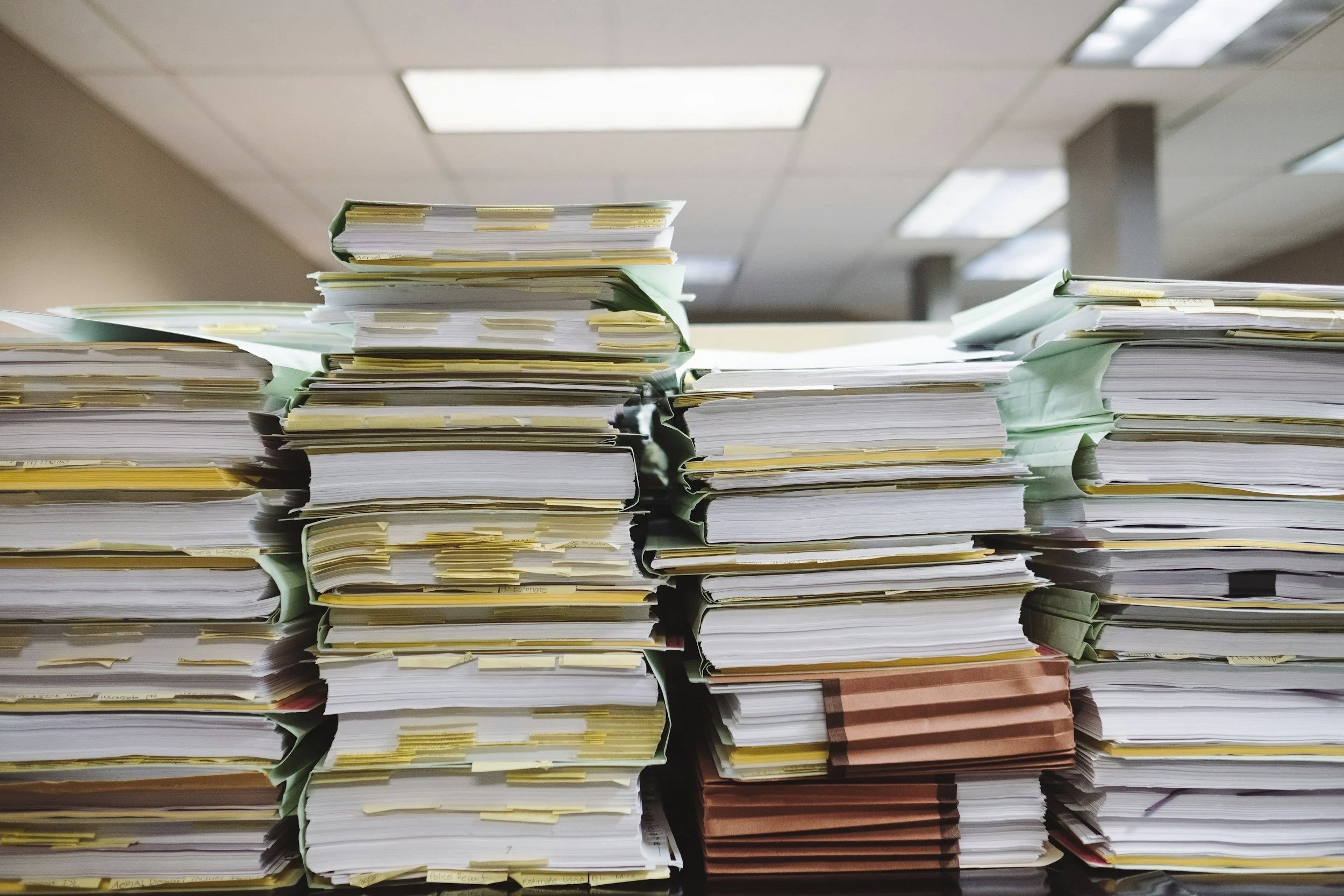 Stacks of documents and files representing the cumulative work and process of M&A due diligence.