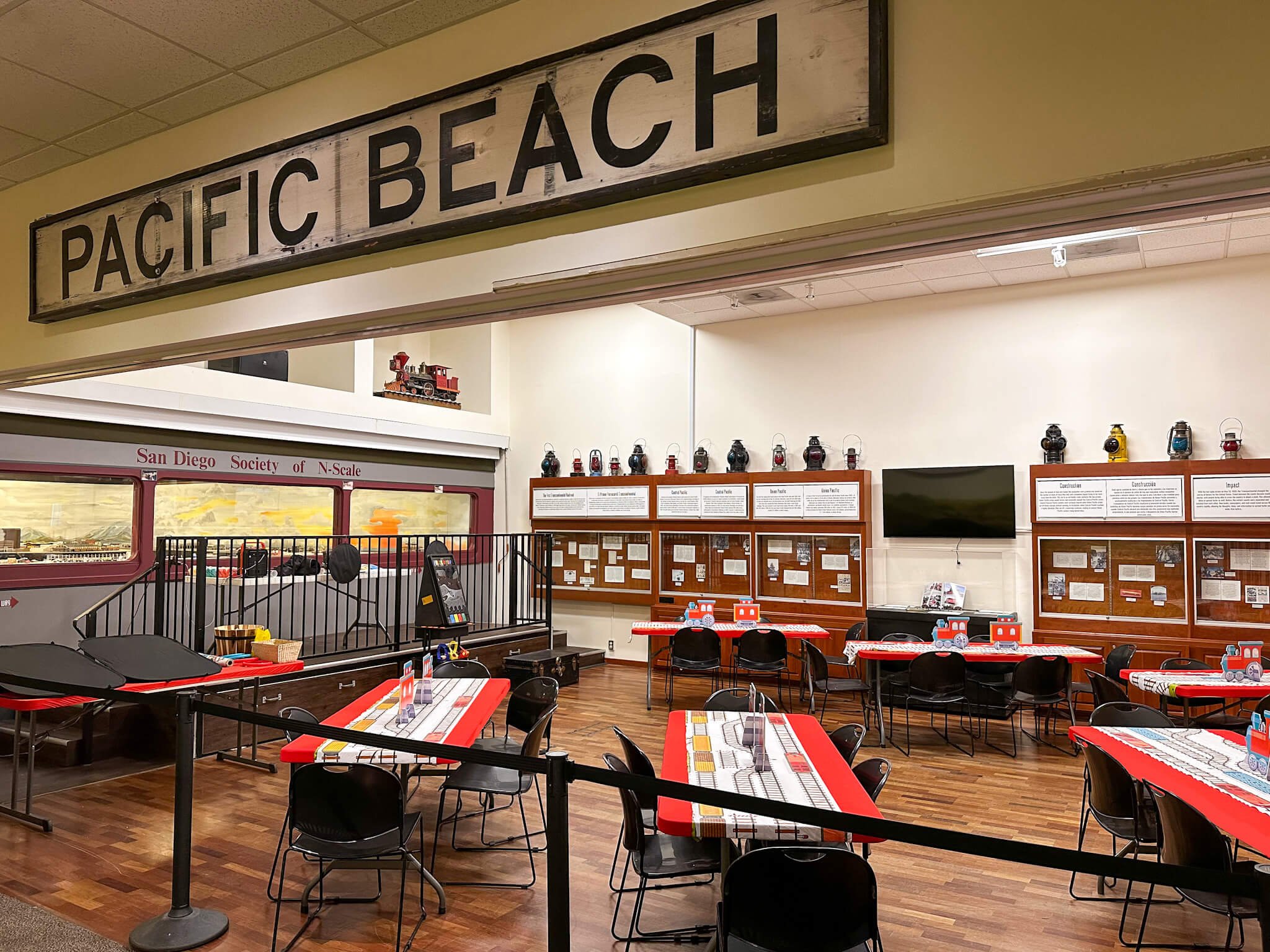  a wide shot of a train-themed birthday party with a sign that says “Pacific Beach” 