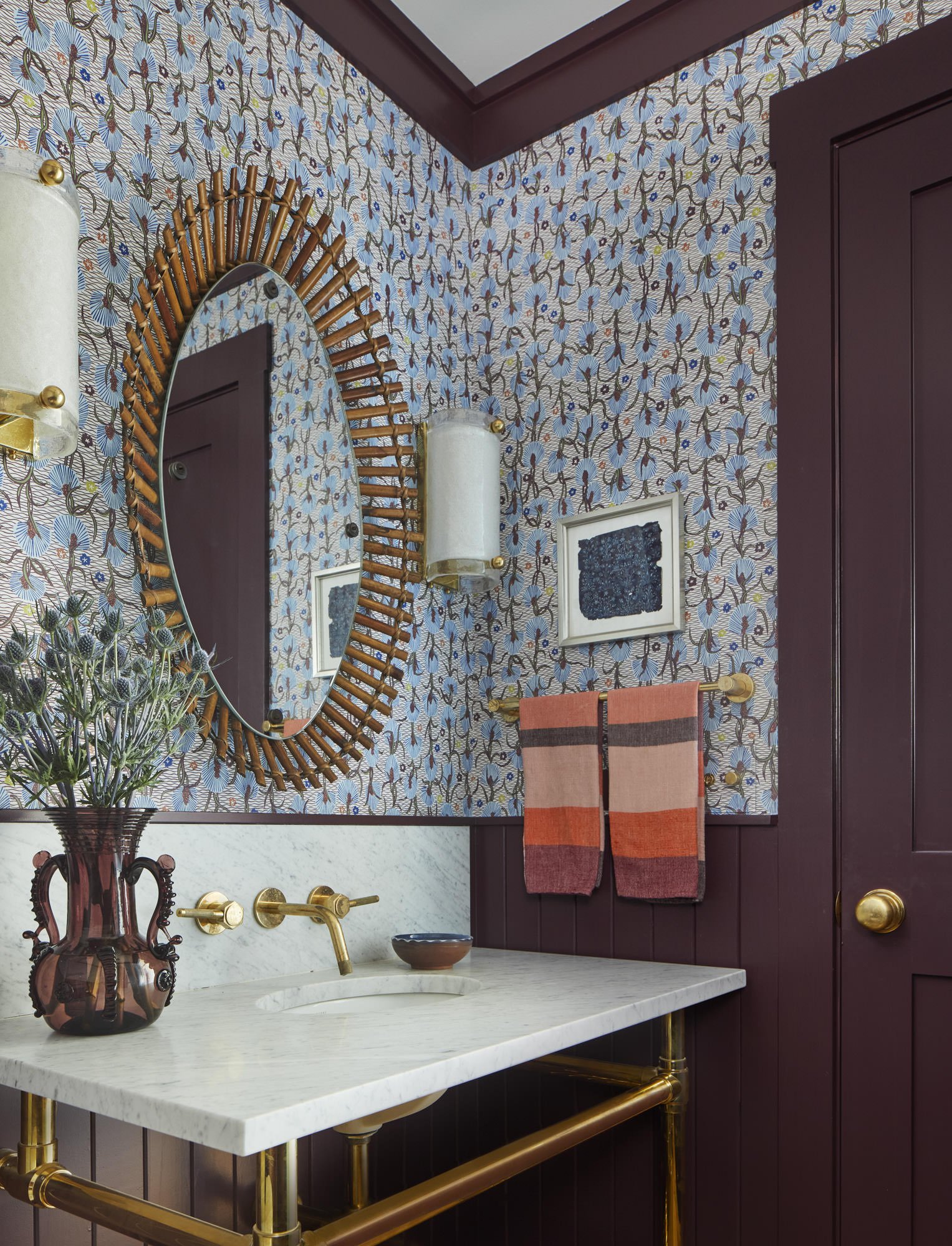   IN THE POWDER ROOM, A CUSTOM BRASS WASHSTAND AND CARRARA MARBLE COUNTERTOP OFFSETS WALLPAPER FROM PIERRE FREY AND A VINTAGE SCULPTURAL BAMBOO MIRROR FLANKED BY A PAIR OF VINTAGE MURANO GLASS SCONCES.  