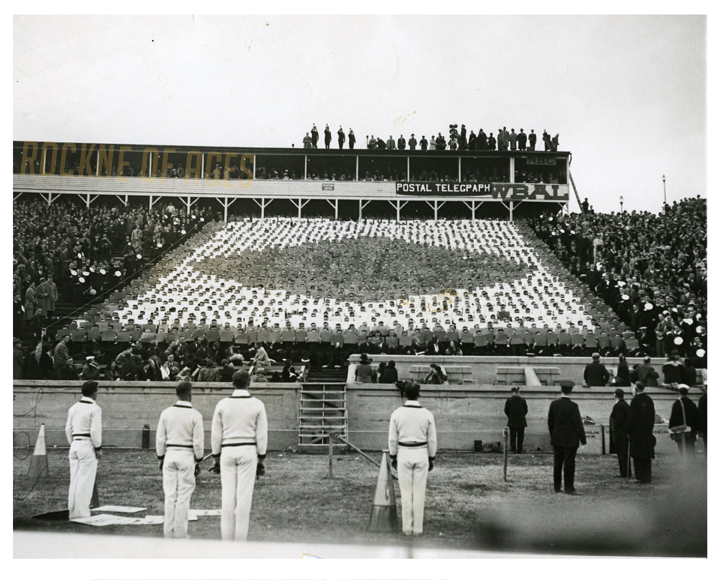  Navy buglers atop the stadium roof in Baltimore blowing taps in memory of the fallen Notre Dame coach while Middies in the stands spell out the name “Knute Rockne” during the Notre Dame-Navy game on Nov. 14, 1931… CREDIT: ACME Photo 