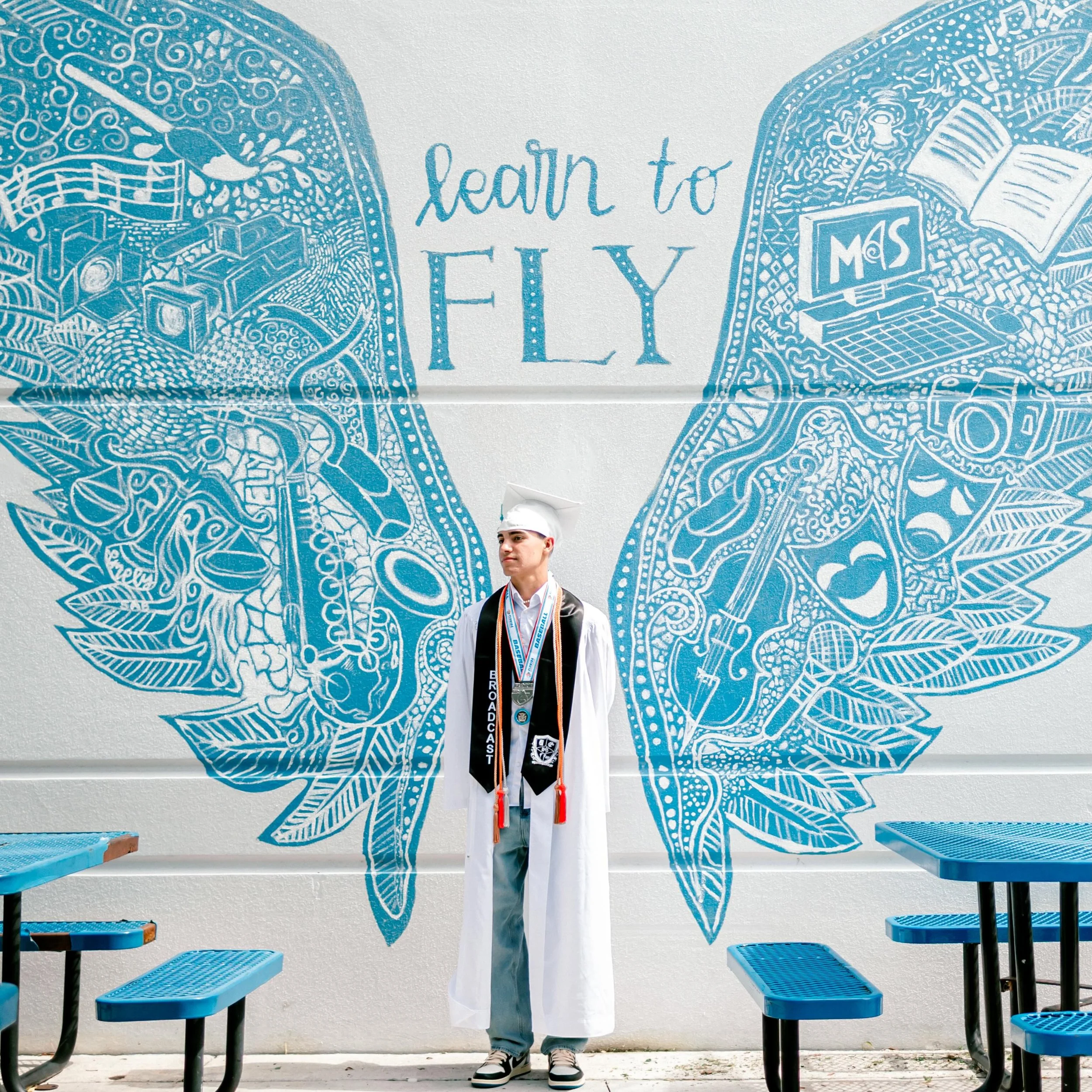The cap and gown signifies a milestone &mdash; they&rsquo;re proof of every quiet sacrifice &amp; every moment you kept becoming who you were meant to be.

And standing in front of those words &mdash; Learn to Fly &mdash; feels bigger now. 
Because b