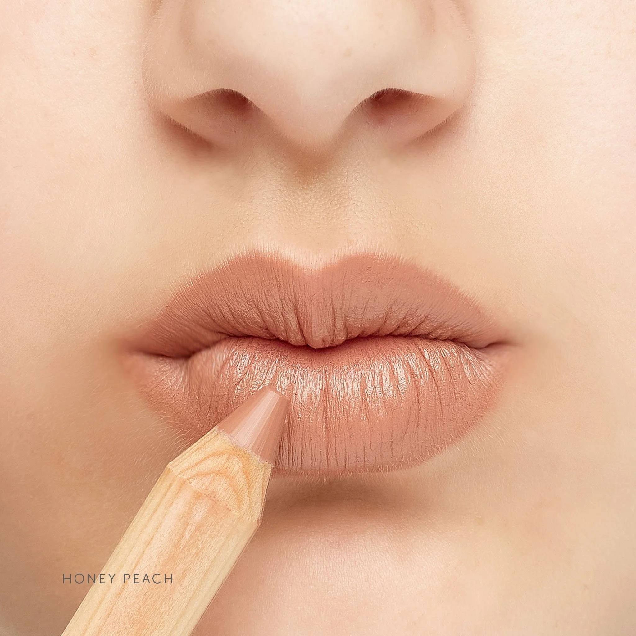 LÜK_LipstickCrayon_HoneyPeach_OnLips_withPencil_ShadeName.jpg